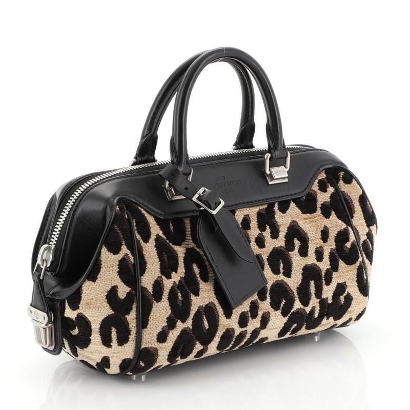This Louis Vuitton Baby Bag Limited Edition Stephen Sprouse Leopard Chenille, crafted in leopard print on chenille fabric with black leather trims, features an angular silhouette, dual-rolled handles, and aged silver-tone hardware. Its zip-around