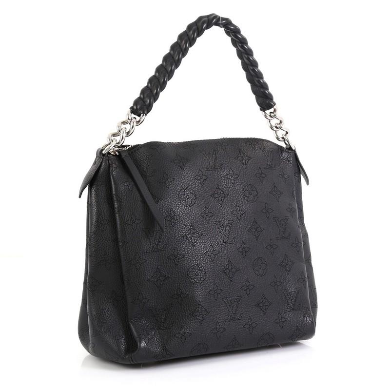 This Louis Vuitton Babylone Handbag Mahina Leather BB, crafted from black mahina monogram perforated leather, features leather-covered chain strap, elegant pleats, protective base studs and silver-tone hardware. Its zip closure opens to a brown