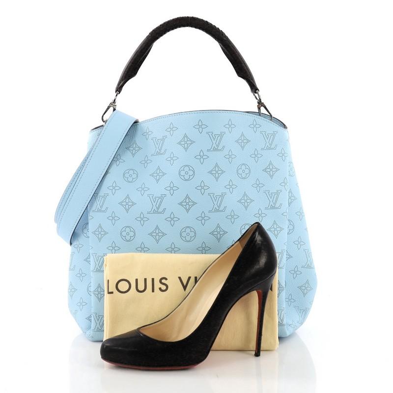 This Louis Vuitton Babylone Handbag Mahina Leather PM, crafted in blue mahina leather, features a braided leather top handle with woven trim and silver-tone hardware. Its wide open top showcases a brown microfiber interior with zip and slip pockets.