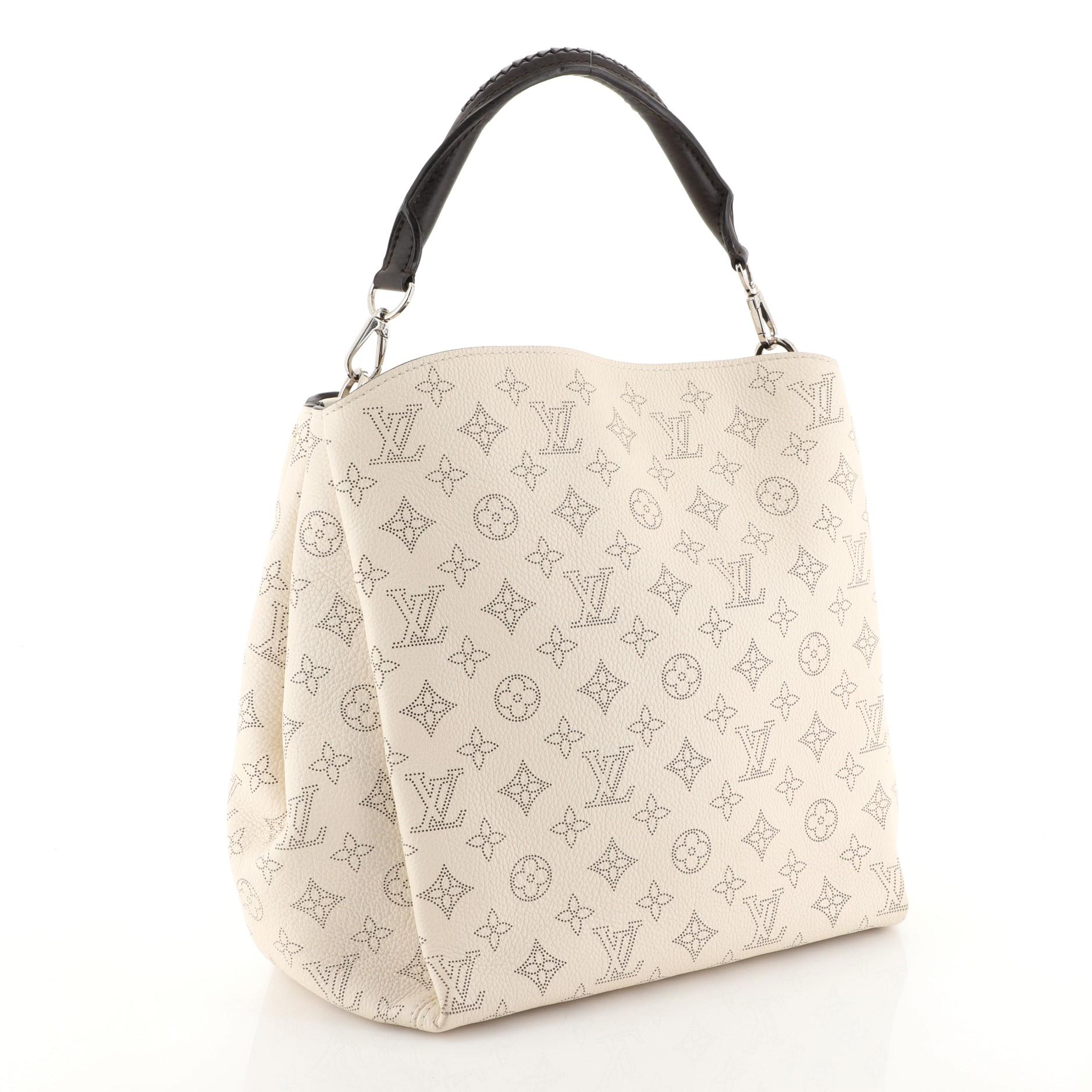 This Louis Vuitton Babylone Handbag Mahina Leather PM, crafted in neutral mahina leather, features a braided leather top handle and silver-tone hardware. It opens to a brown microfiber interior with zip and slip pockets. Authenticity code reads: