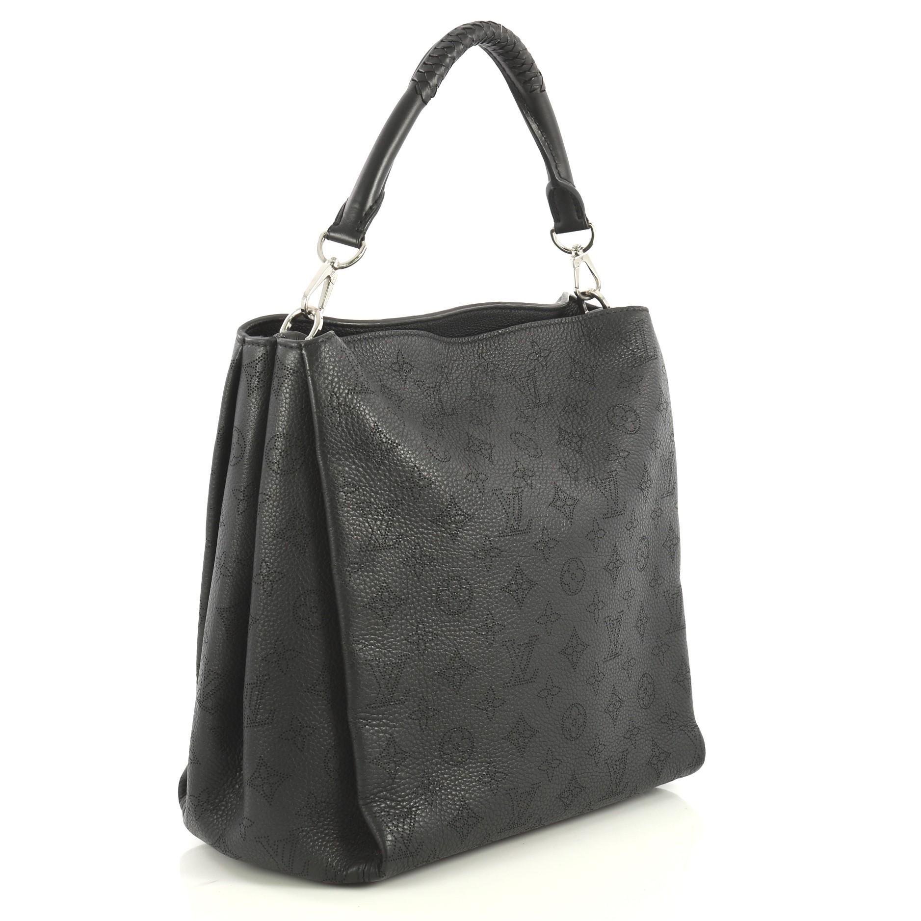This Louis Vuitton Babylone Handbag Mahina Leather PM, crafted in black mahina leather, features a braided leather top handle with woven trim and silver-tone hardware. It opens to a neutral microfiber interior with zip and slip pockets. Authenticity