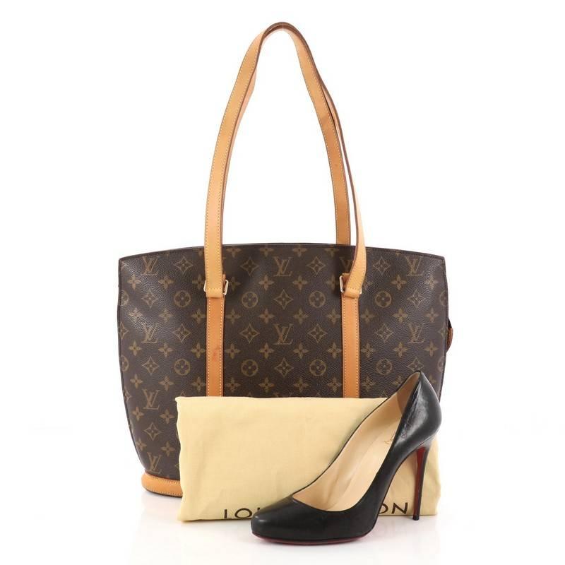 This authentic Louis Vuitton Babylone Handbag Monogram Canvas is a stylish and durable tote ideal for everyday use. Crafted from brown monogram coated canvas, this bag features natural vachetta cowhide leather straps and trims, gold-tone hardware