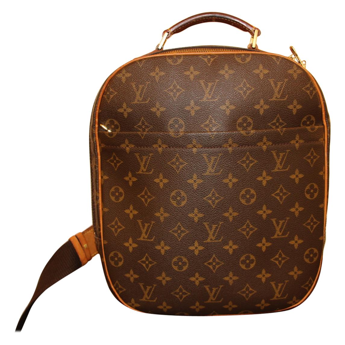This very nice backpack bag features monogram canvas. It can be carried by men or women. The bag features a wide frontal pocket, cowhide leather trim and a sturdy leather top handle with an adjustable long nylon shoulder strap and polished brass
