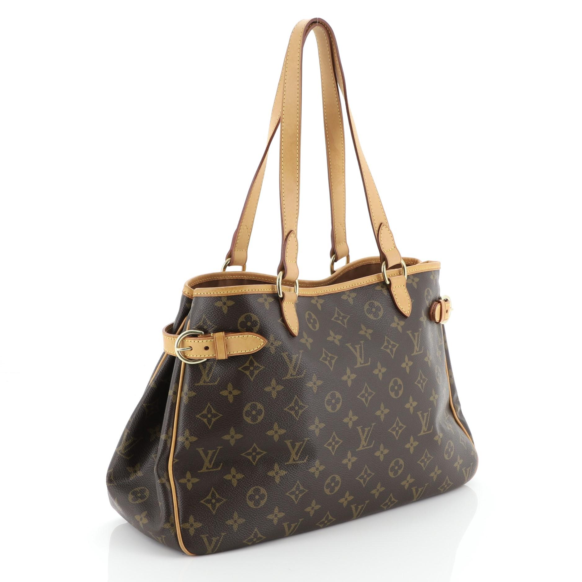 This Louis Vuitton Batignolles Handbag Monogram Canvas Horizontal, crafted in brown monogram coated canvas, features cowhide leather handles and trim, side belt strap details, and gold-tone hardware. It opens to a brown fabric interior with zip and