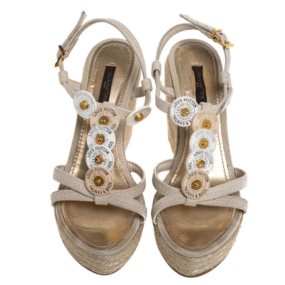 Marchez avec confort dans ces charmantes sandales Louis Vuitton ! Ces sandales ont été fabriquées en toile et sont ornées de médaillons sur les empeignes. Elles sont dotées d'une fermeture à la cheville et de talons compensés en forme