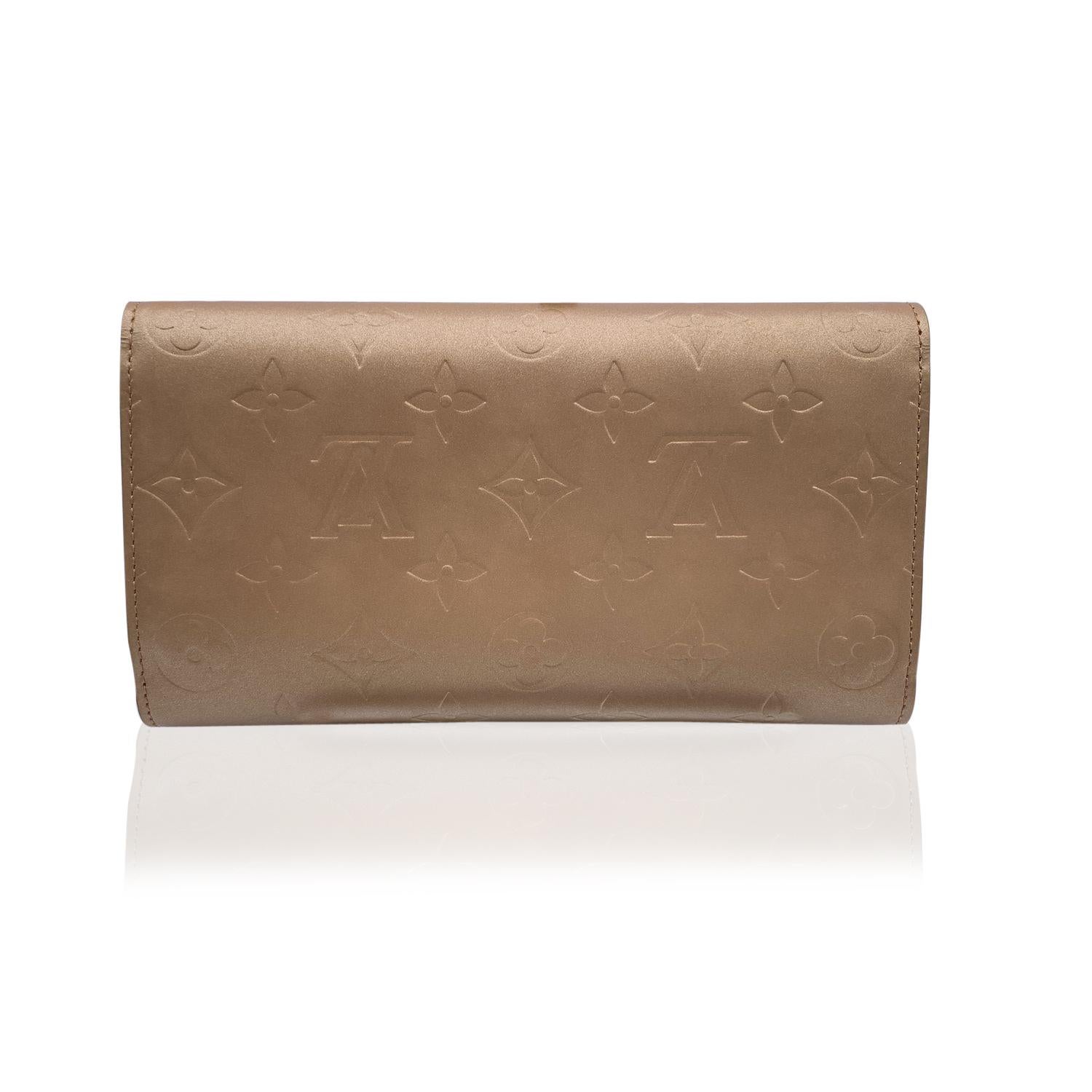 Louis Vuitton long wallet Mod. 'Porte Tresor International Organizer' in beige monogram mat leather. Flap with button closure. Inside: 2 open pockets, 6 credit card slots,1 coin section (flap with button closure), 1 pen compartment. 'LOUIS VUITTON