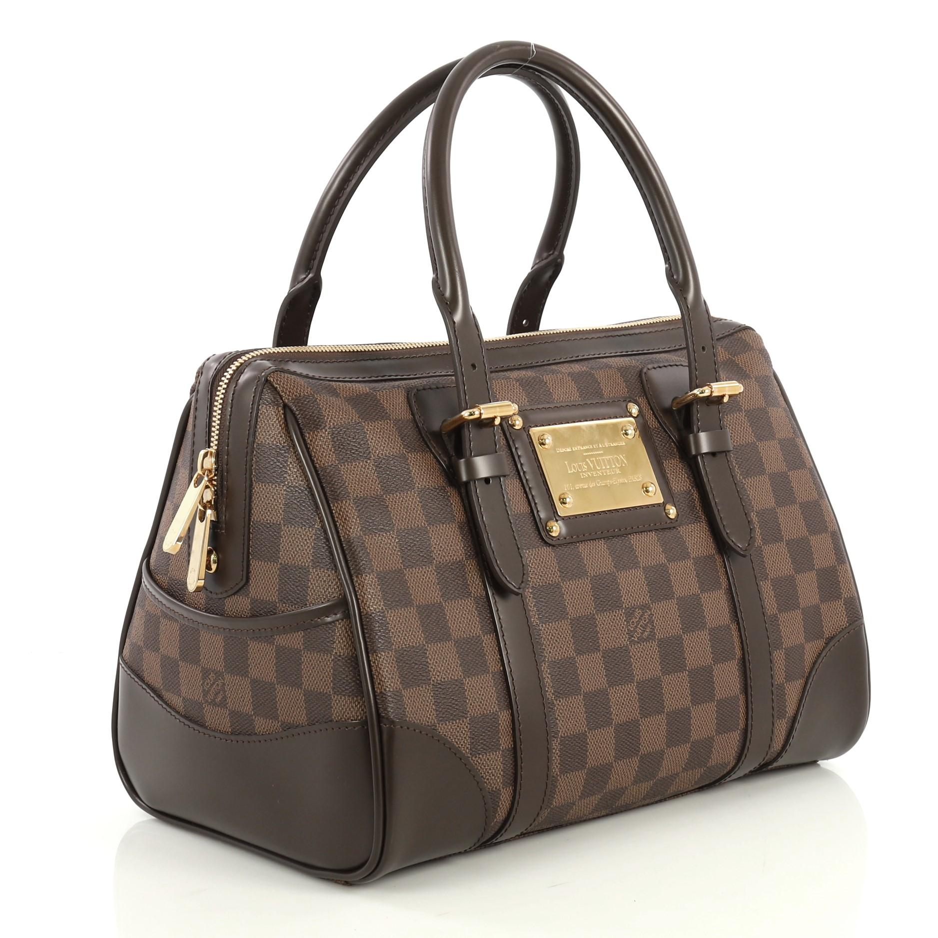 This Louis Vuitton Berkeley Handbag Damier, crafted from damier ebene coated canvas, features dual rolled leather handles with belt and buckle details, exterior side pockets, and gold-tone hardware. Its zip closure opens to a red microfiber interior
