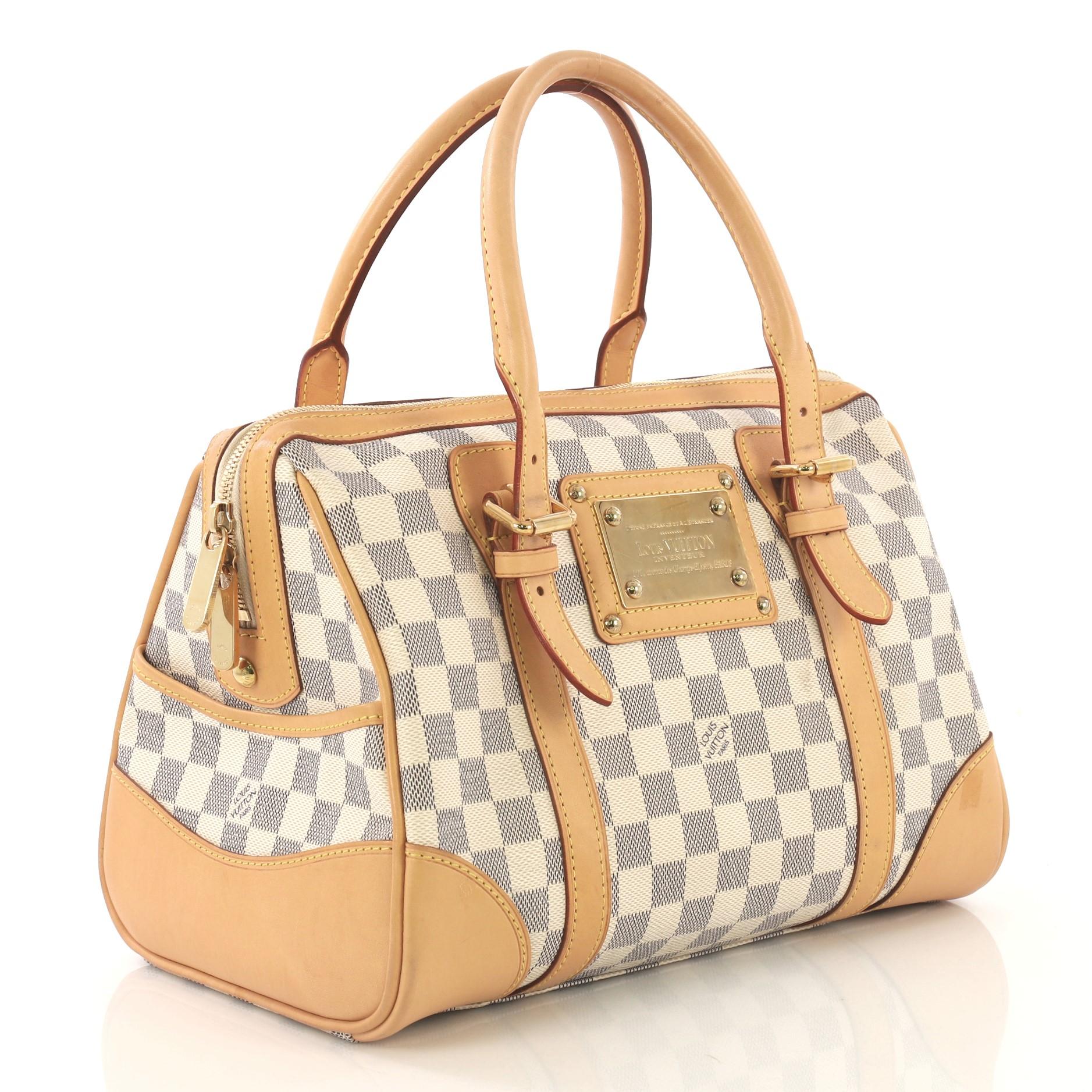 This Louis Vuitton Berkeley Handbag Damier, crafted from damier azur coated canvas, features dual rolled leather handles with belt and buckle details, exterior side pockets, and gold-tone hardware. Its top zip closure opens to a beige microfiber