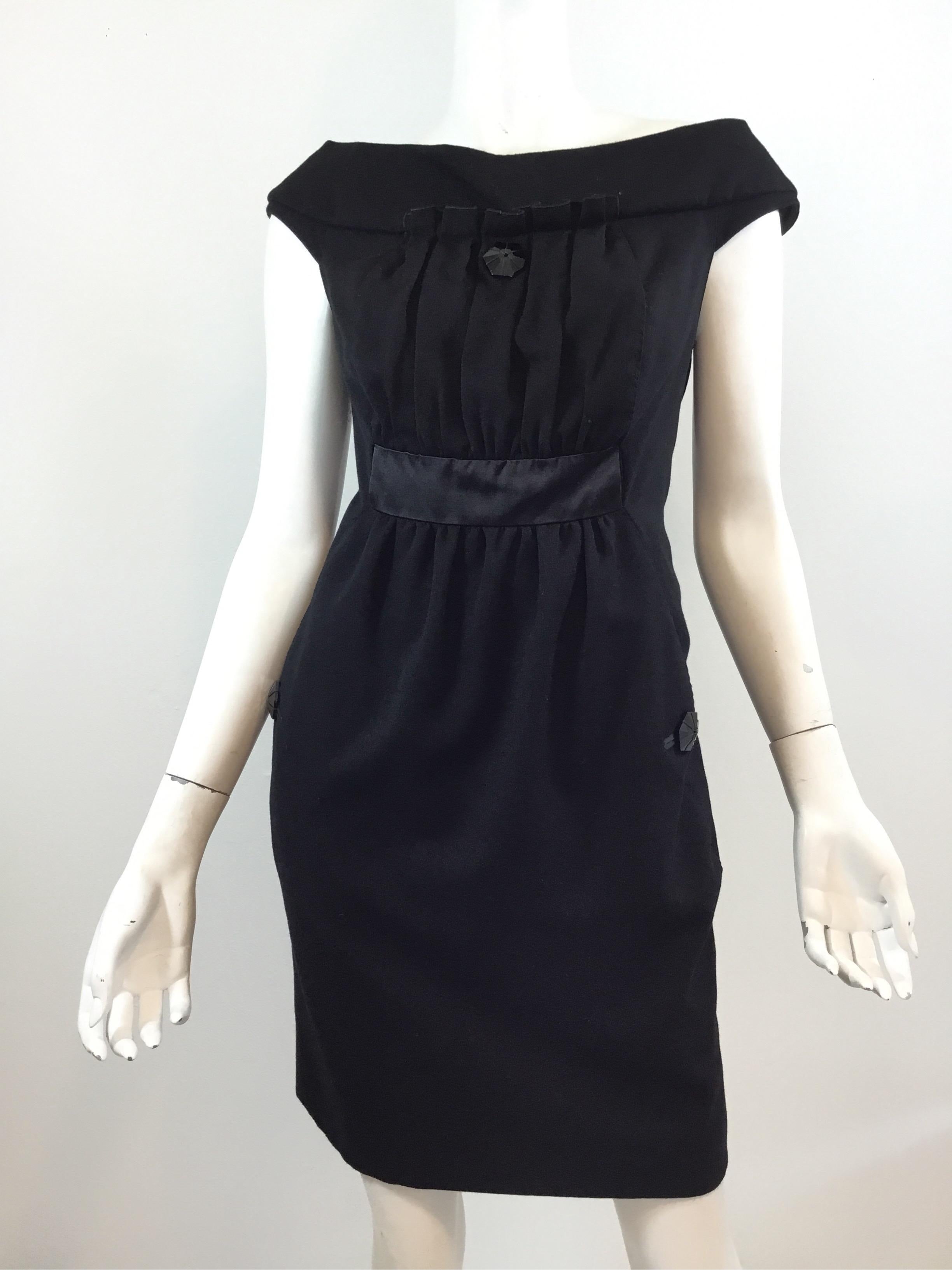 Louis Vuitton little black dress with large bead embellishing at the center neckline and at the pockets. Dress features a boat neck style and a satin band at the waist line with insert holes for a belt. Dress has a full silk lining and back zipper
