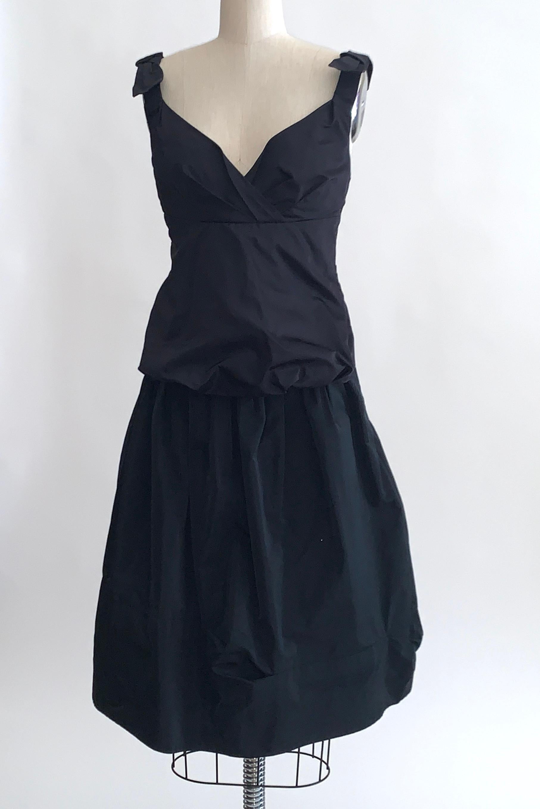 Louis Vuitton black shirt and skirt set. Tank features a bubble style hem and bows at each shoulder with pleat detailing at bust. Seam detail at back. Top fastens at back with hook and eye closures from top to bottom. Skirt features a velvet