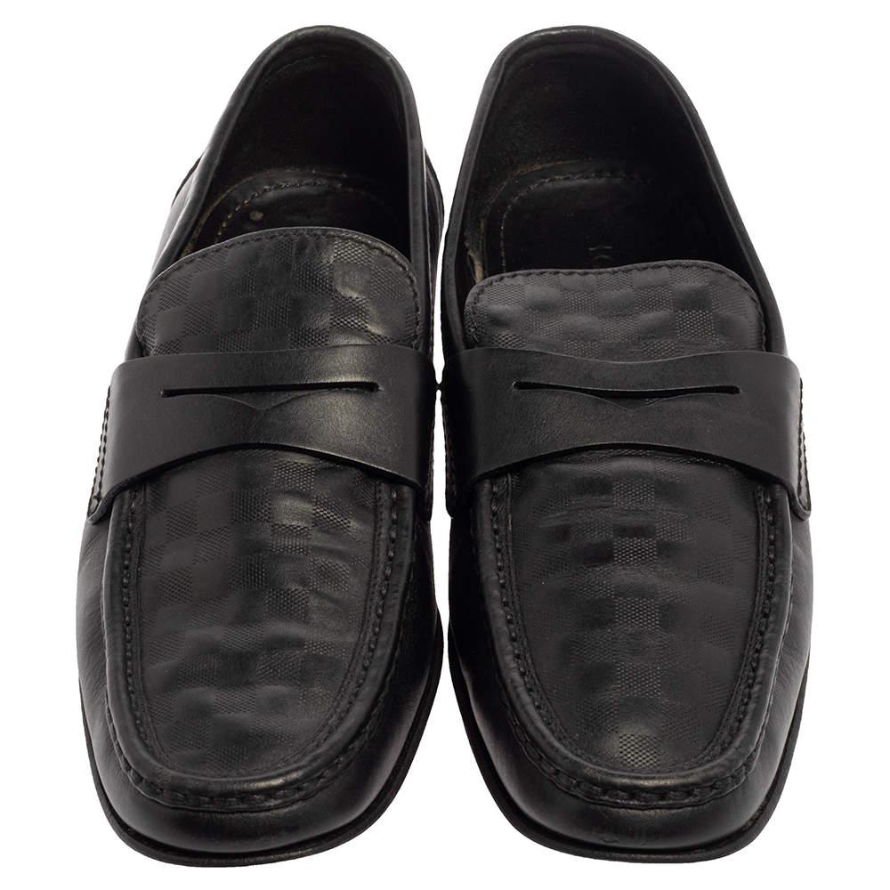 Diese zeitlosen Santiago Loafers lassen Sie elegant und gepflegt aussehen. Sie sind aus glänzendem schwarzem Leder mit Damier-Prägung auf dem Vorderblatt gefertigt und mit Penny-Riemen versehen. Die Innensohlen sind mit Leder gefüttert und mit Louis