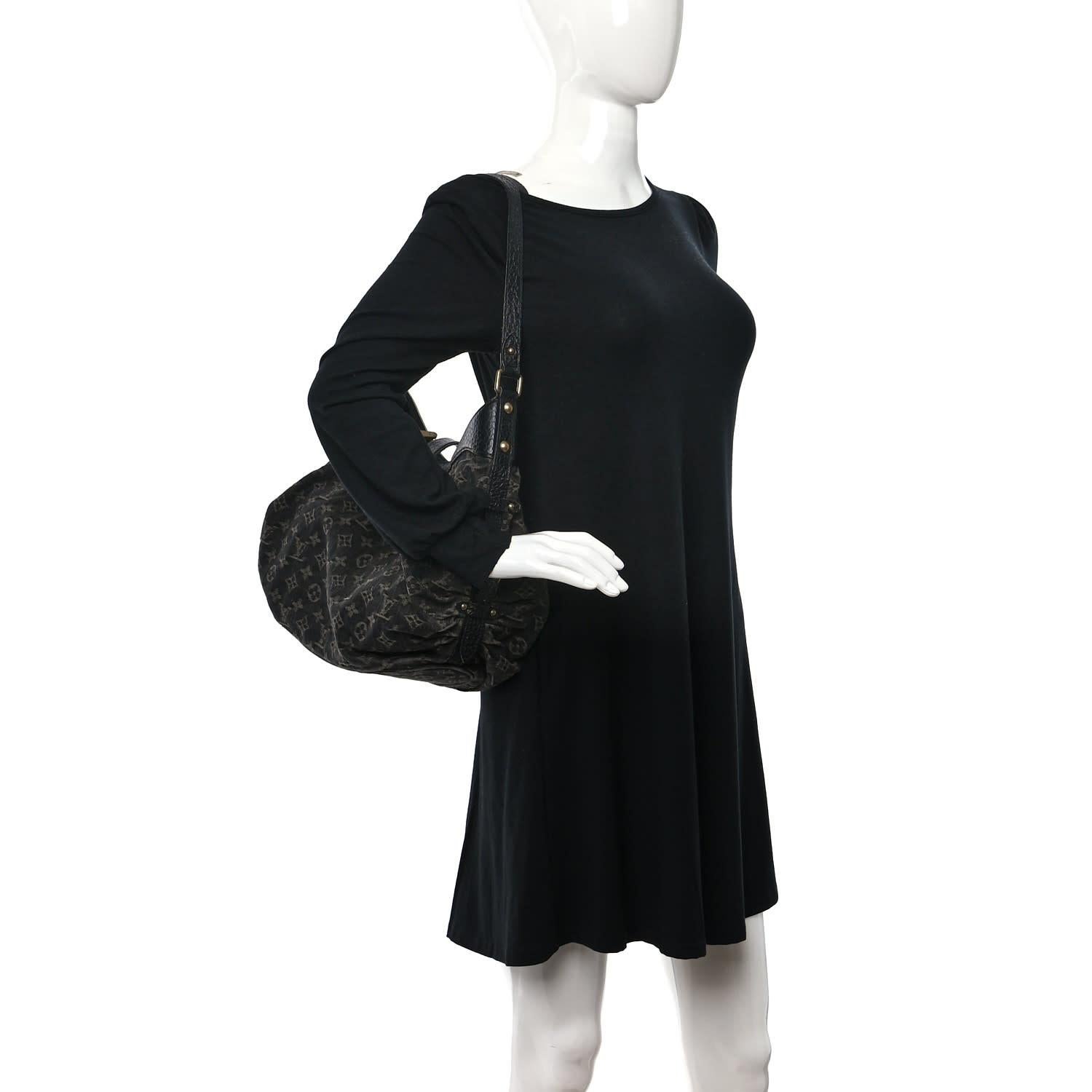 This shoulder bag is made of black monogram denim fabric. It is gathered at both sides with a stylish draped effect supported with black leather trim. The bag features an adjustable leather shoulder strap and aged brass hardware. The top zipper