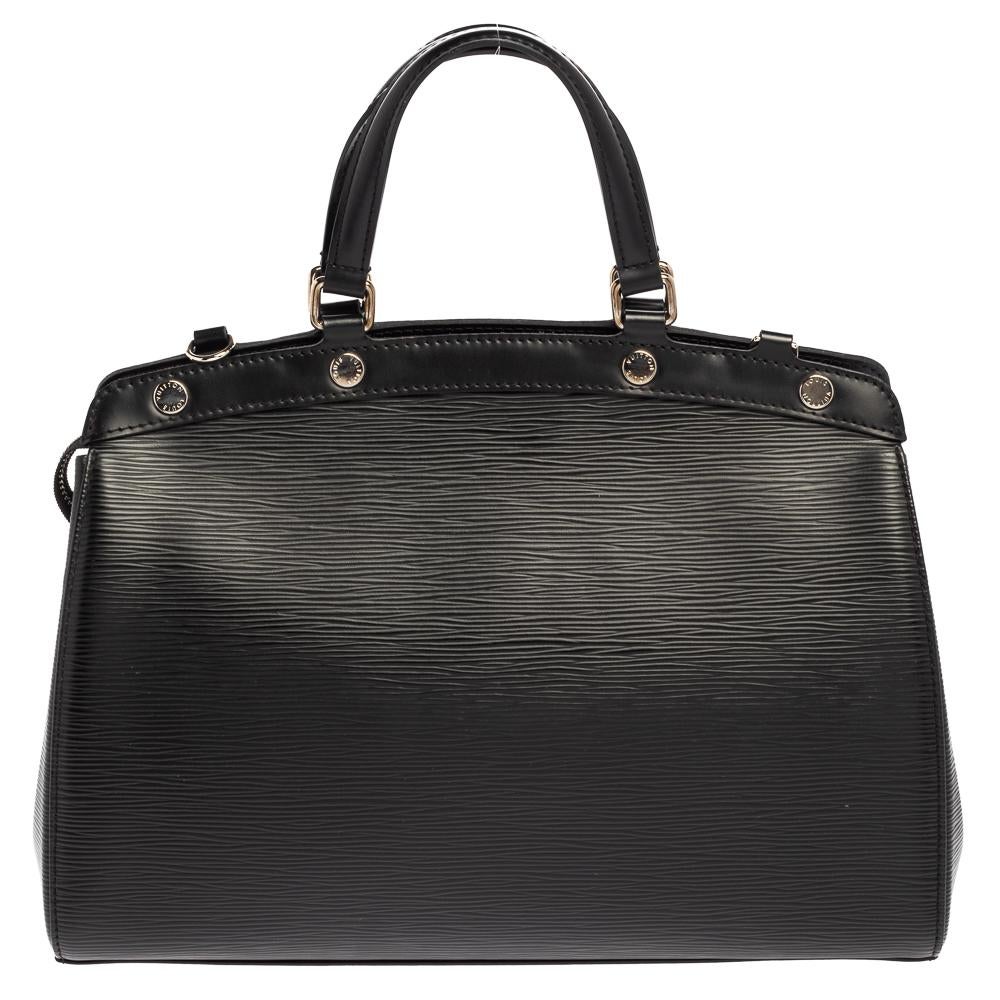 The feminine shape of Louis Vuitton's Brea is inspired by the doctor's bag. Crafted from Epi leather in black, the bag has a perfect finish. The fabric interior is spacious and it is secured by a zipper. The bag features double handles, protective