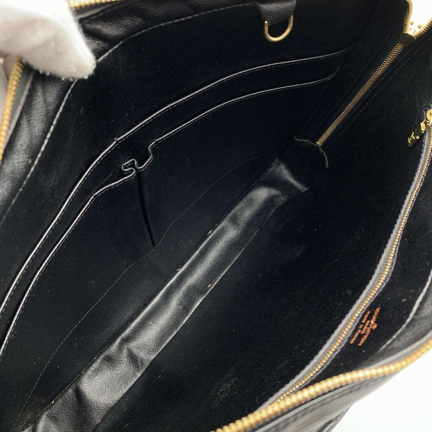 LOUIS VUITTON soft briefcase, mod. 'Porte-Document Voyage' in Black epi leather. Gold hardware. Wrap around double zipper. Padlock included but no keys. The interior is lined in leather with1 side zip pocket inisde, 4 open pockets, 1 D ring. 'Louis