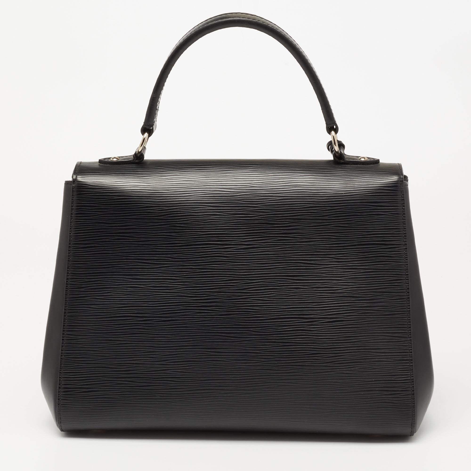 This Cluny MM from the House of Louis Vuitton is designed to lend elegance, class, and poise. It is made from black Epi leather on the exterior. It flaunts a roomy Alcantara-lined interior and a top handle. It is fitted with gold-tone hardware.