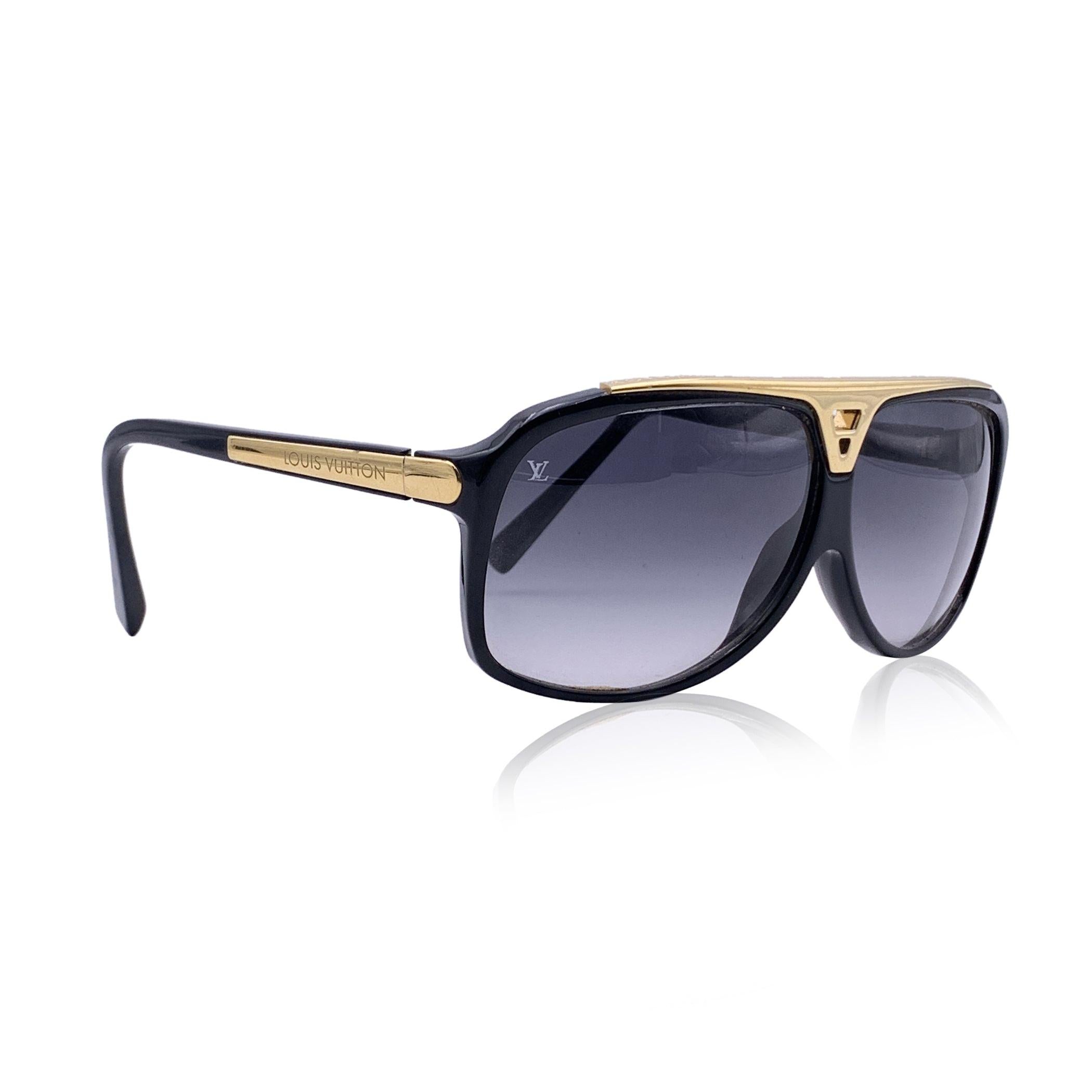 Gafas de sol Louis Vuitton, mod. Z0350E Evidence, de la colección 2011. Montura de acetato de aviador en color negro con detalles metálicos dorados. Símbolos icónicos de Louis Vuitton grabados en la parte superior de las gafas de sol. Bisagras