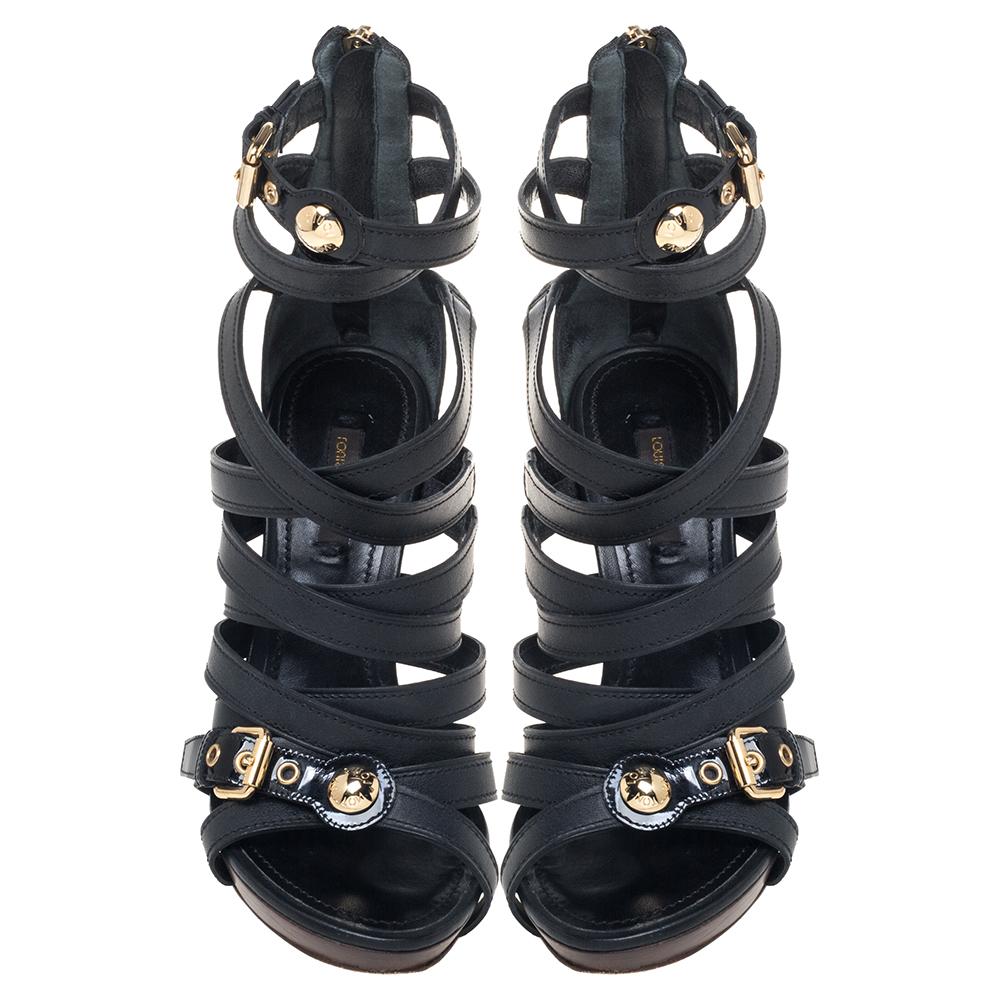 A statement pair of strappy black heels will easily pair with any special look be it day or night. These Louis Vuitton sandals designed in black leather feature a crisscross design with shiny buckles in gold-tone metal. They are lifted on 11.5 cm