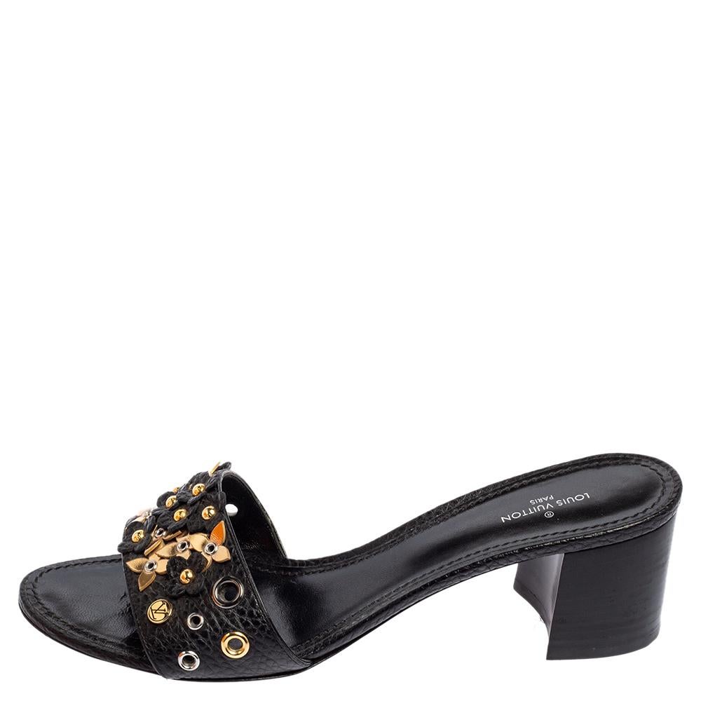 Charm your way to all your social gatherings in this pair of slide sandals from Louis Vuitton. Crafted from black leather, they carry a smart design with open toes, applique embellishments on the vamps, and block heels. Comfortable insoles make them