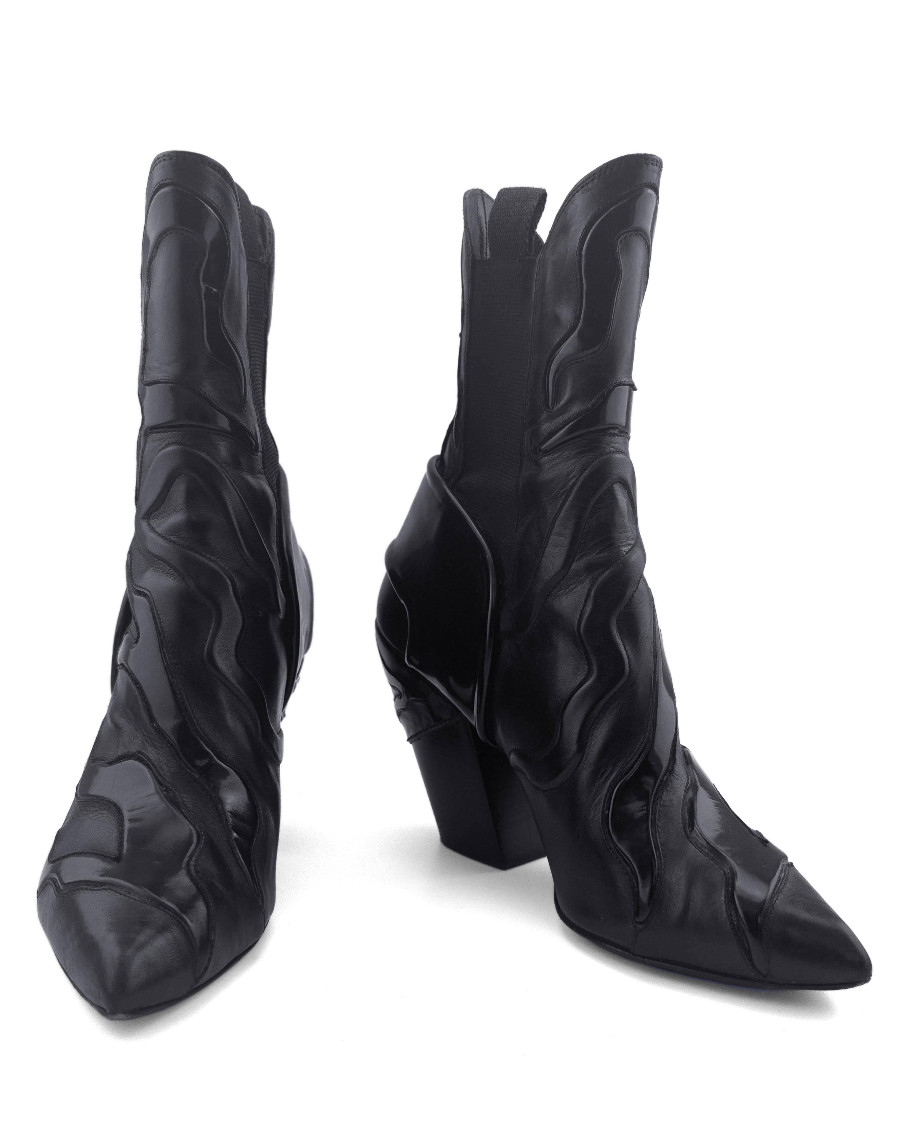 A bold collision of Western rebellion and futuristic design, the Louis Vuitton Fireball boots from 2018 channel high-impact energy with every detail. Crafted in sleek black leather, these sculptural ankle boots are distinguished by their dramatic