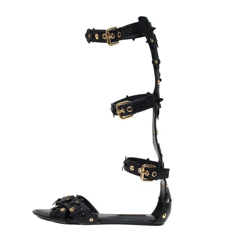 These ultra cool gladiator sandals by Louis Vuitton will have your attire transformed completely. Made from black leather, they feature buckled gladiator straps, gold-tone cone studs and quatrefoil motif detailing, three buckle fastenings and