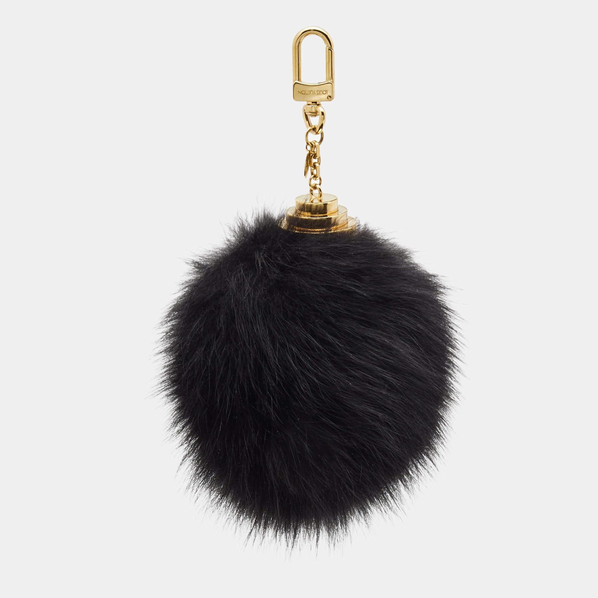 The Louis Vuitton key holder is a luxurious accessory crafted from premium black mink fur. It features the iconic LV monogram pattern in gold-tone hardware and a secure key ring attachment. This elegant piece adds sophistication and style to your