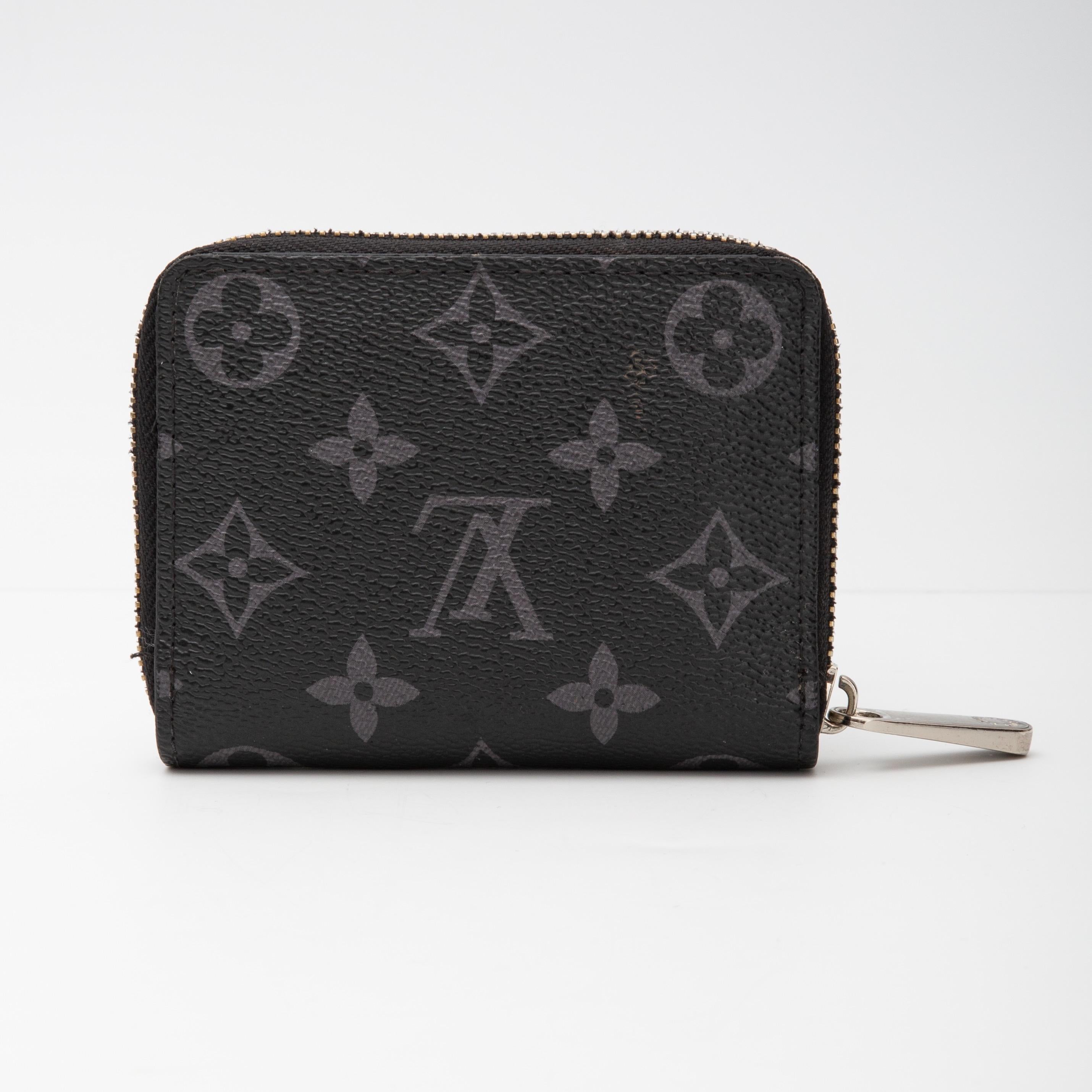 This cardholder/pouch is made of canvas in black with Louis Vuitton's signature monogram in grey. A silver wrap around zipper opens to a black cross-grain leather interior with a many card slot panels.

COLOR: Black
MATERIAL: Coated canvas
DATE