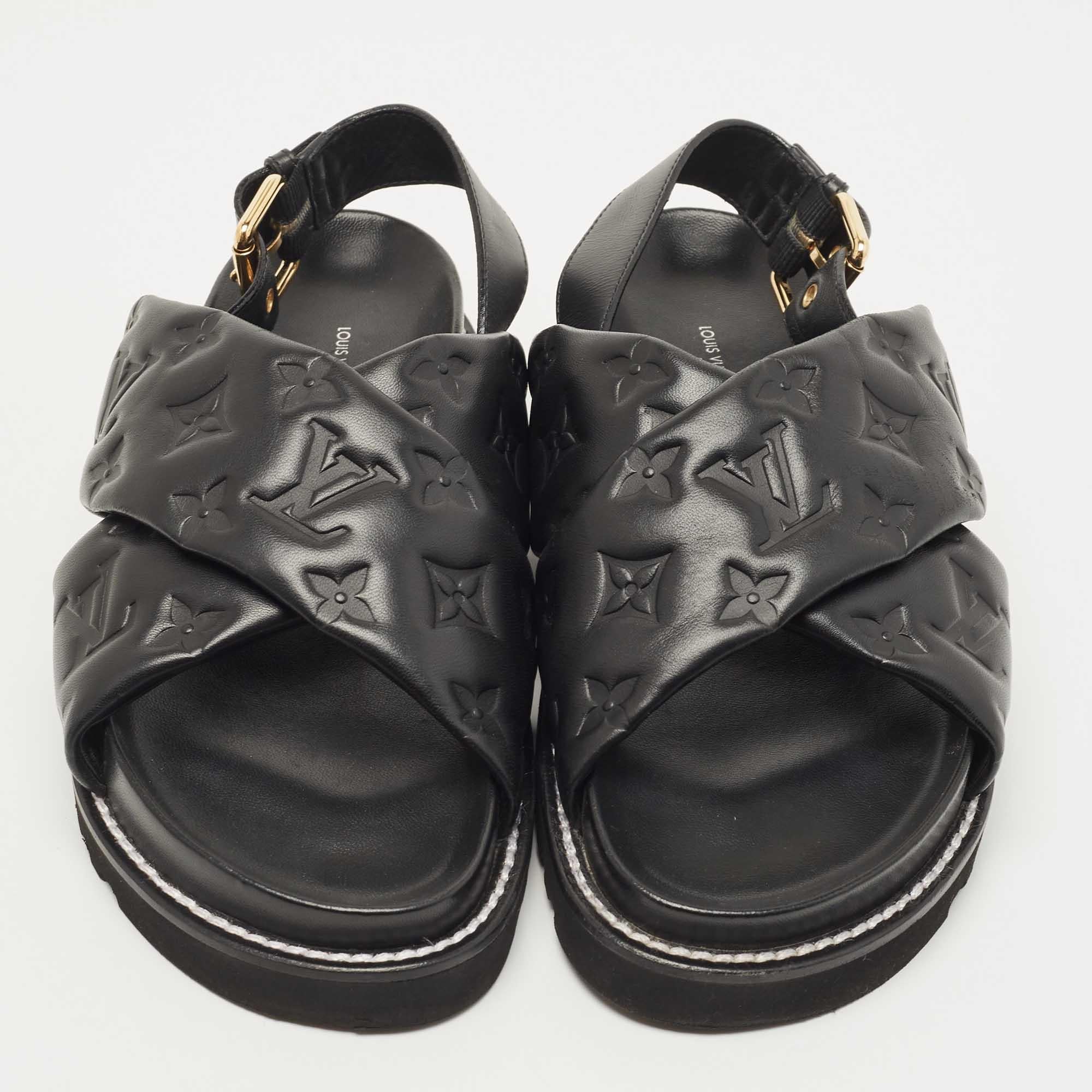 The Louis Vuitton Paseo flats are exquisite footwear, featuring the iconic LV monogram pattern embossed onto black leather. These elegant sandals offer comfort and style with a flat sole and a sleek, minimalist design, making them a luxurious