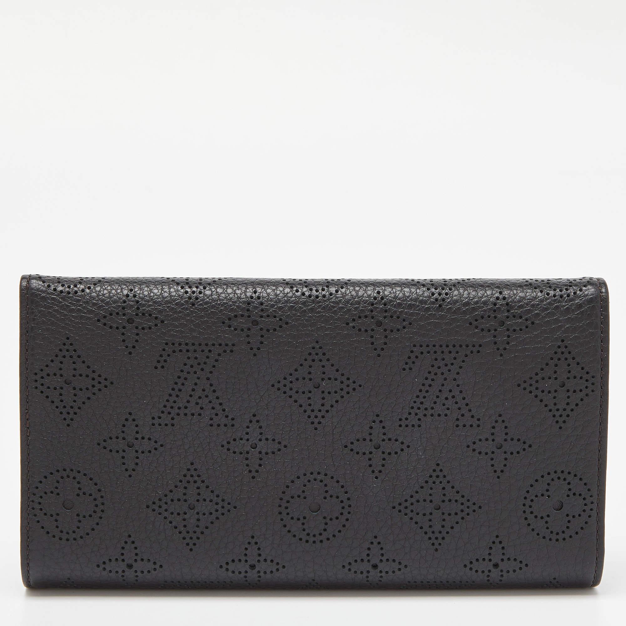 The gorgeous Amelia wallet has a flap design with a gold-tone lock to secure the interior. Made from black monogram Mahina leather, this Louis Vuitton creation features multiple card slots, a zipped compartment for change, and enough space for your