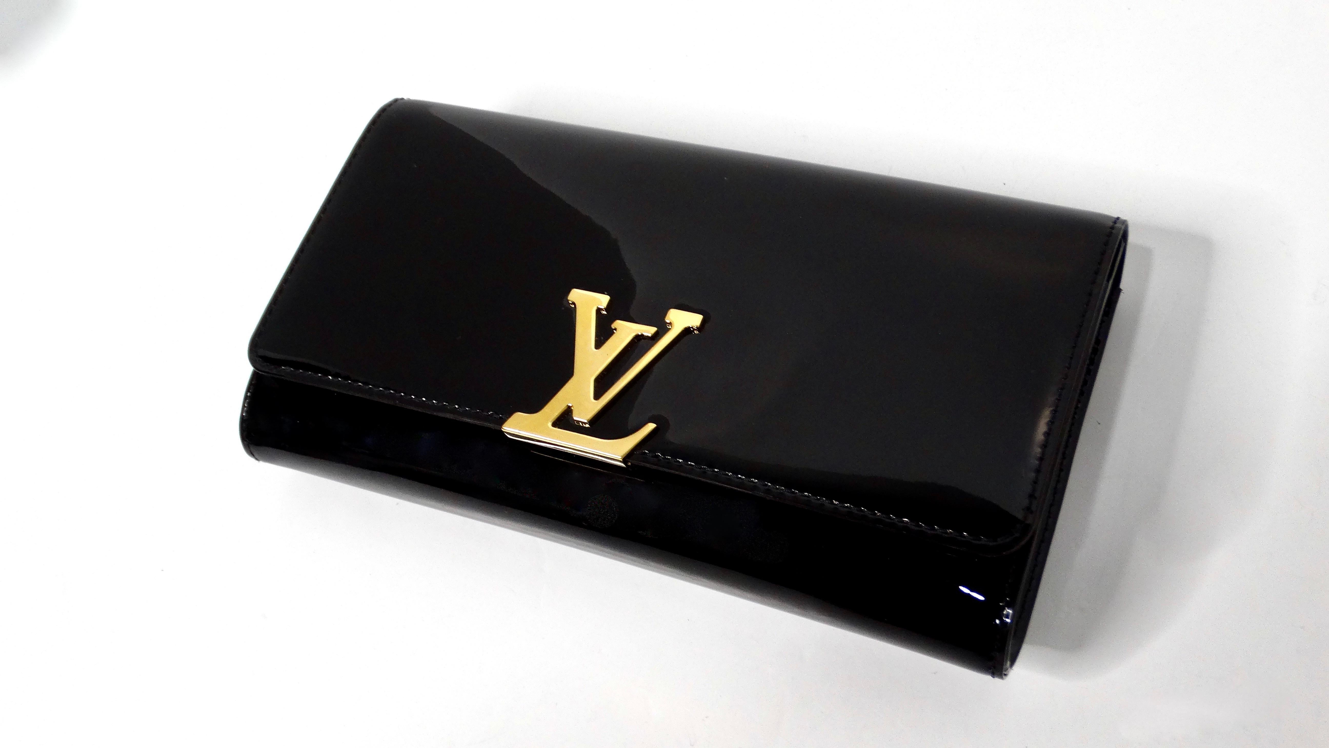 The Louis Vuitton Black Patent Leather Louise Clutch is a timeless and sophisticated accessory that exudes understated luxury. Crafted from high-shine patent leather, this clutch boasts a sleek and structured silhouette that is perfect for evening