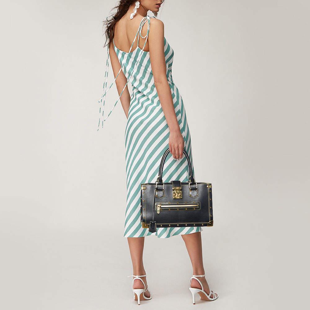 Louis Vuitton's Le Fabuleux bag looks nothing like a regular Louis Vuitton bag! Rectangular in shape, the bag is crafted from black Suhali leather and has stud embellishments. It features dual top handles, a front zip pocket, and the S lock closure.