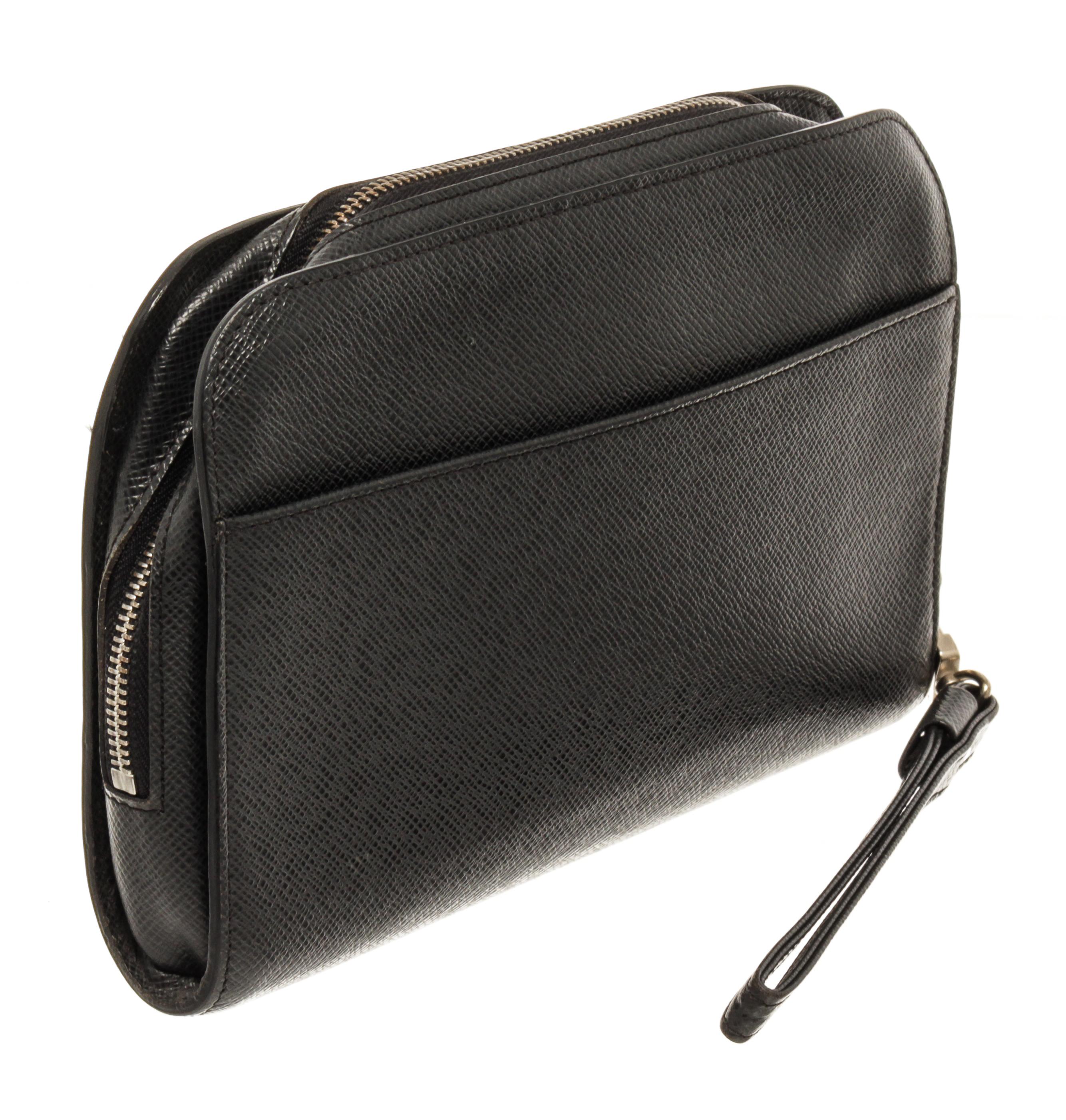 Louis Vuitton Black Taiga Leather Orsay Wrist Clutch with silver-tone hardware, black taiga leather trim, exterior slip pocket at back, black leather lining, interior slip pocket, detachable black leather wrist strap, and zipper closure at the top.