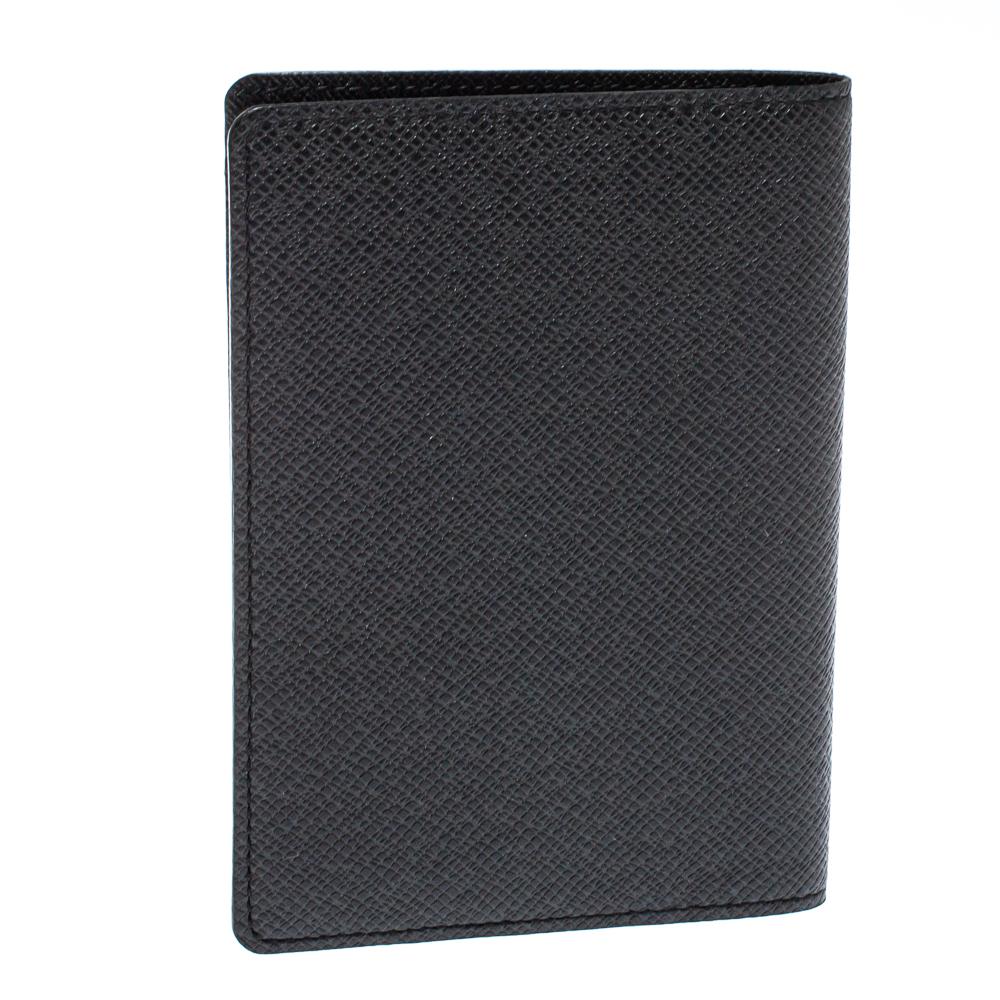 Louis Vuitton never fails to impress! This passport holder comes crafted from black taiga leather and opens to a leather interior that houses two side slots for the passport to fit and additional card slots. Finished with neatly stitched edges, this