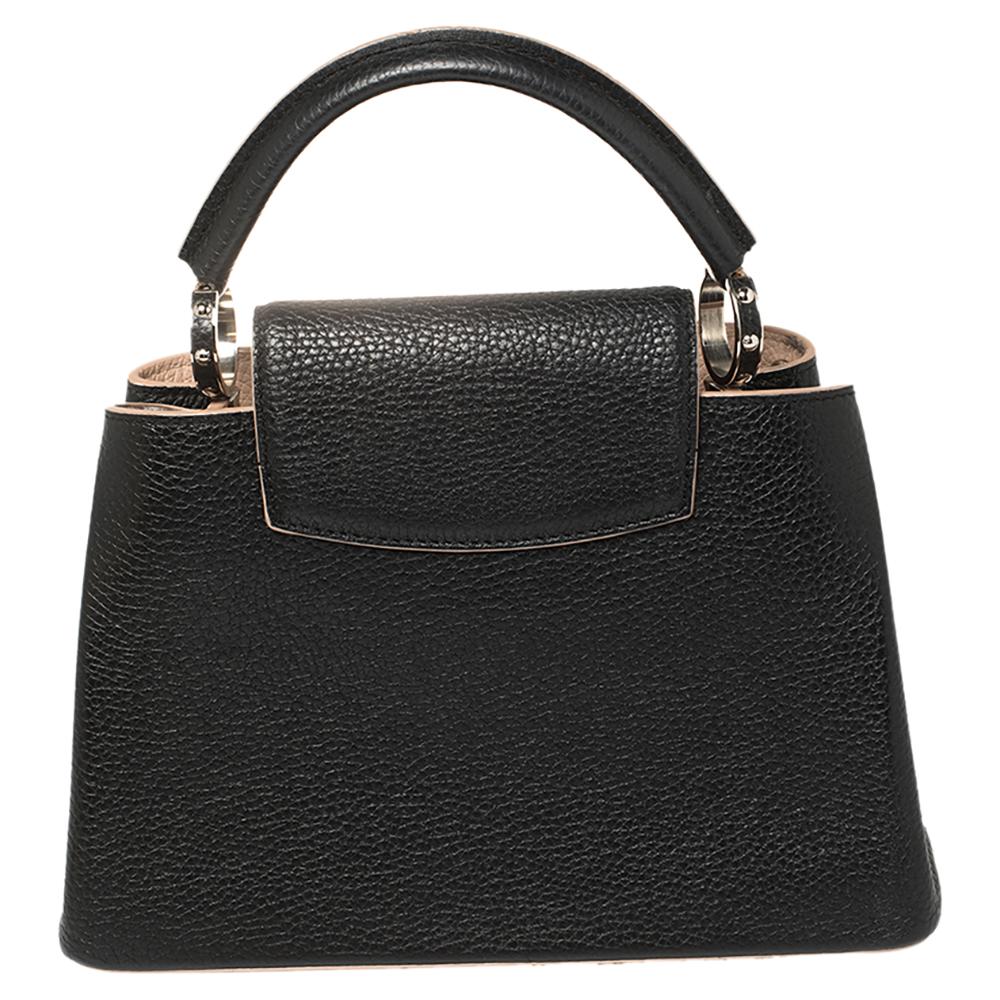It is every woman's dream to own a Louis Vuitton handbag as appealing as this one. Crafted from Taurillon leather, this bag features a structured design with a single handle and protective metal feet. While the front LV elevates its beauty, the