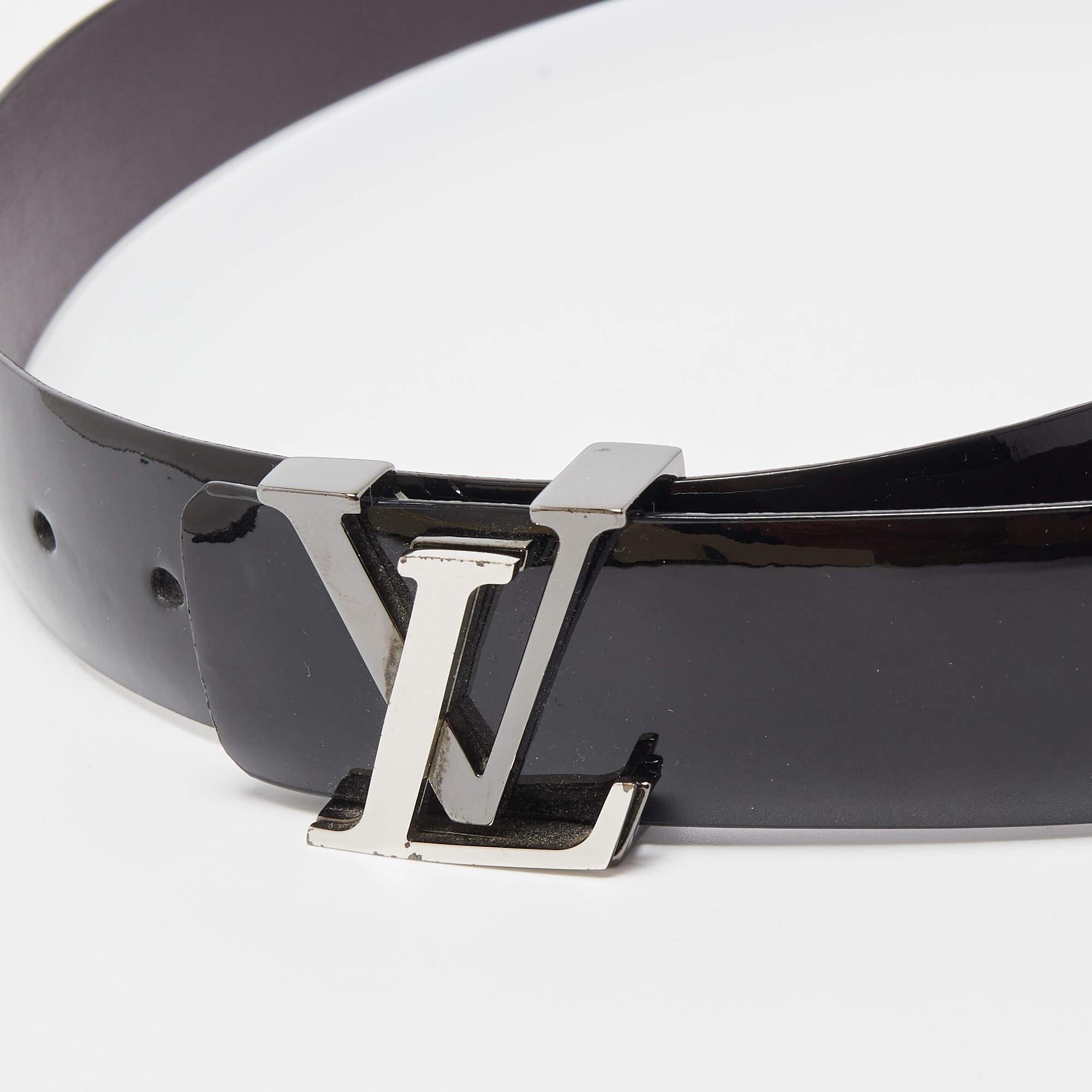 The Louis Vuitton LV Initiales belt is a luxurious fashion accessory crafted from glossy black Vernis patent leather. It features the iconic LV initials as a prominent buckle, making it a statement piece that adds sophistication and style to any