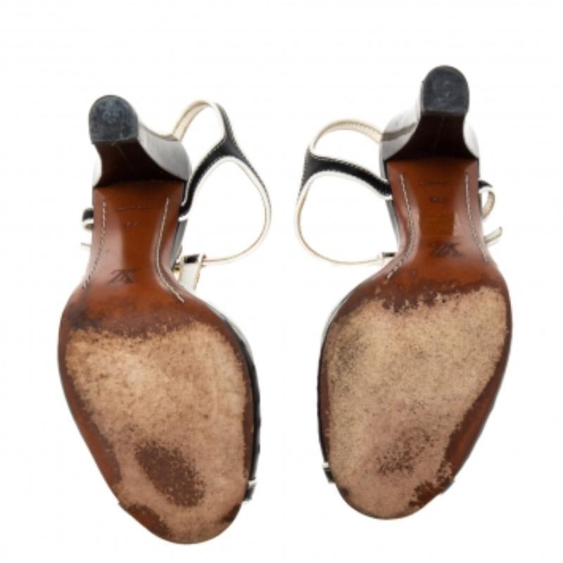 Keep luxury, style, and class at a maximum with these beautiful sandals from the House of Louis Vuitton. They feature an exterior made from white-black patent leather and flaunt peep-toes, a T-strap, and block heels. Gold-tone hardware is used to