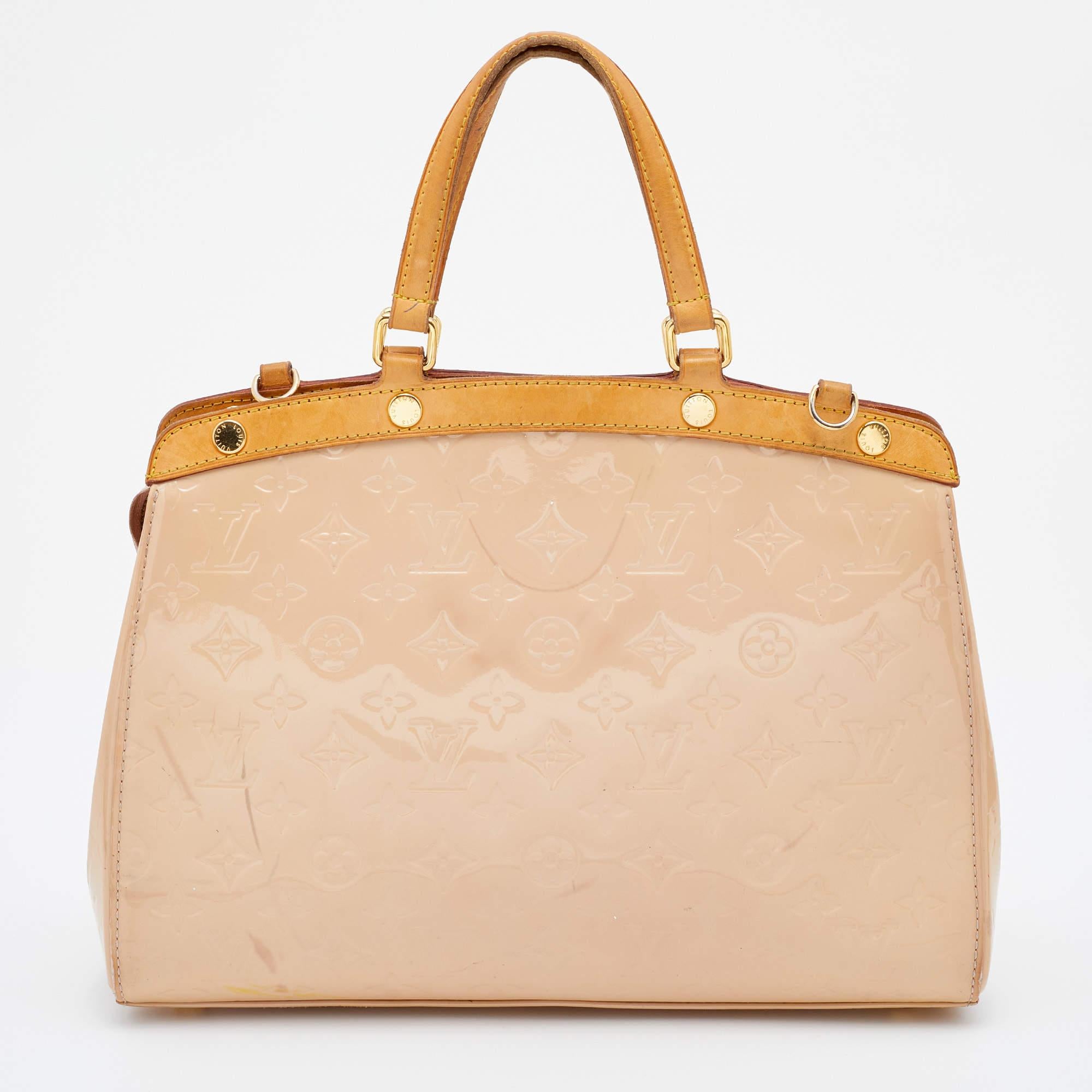 The feminine shape of Louis Vuitton's Brea is inspired by the doctor's bag. Crafted from Monogram Vernis leather, the bag has a fine finish. The fabric interior is spacious, and it is secured by a zipper. The bag features double handles, a shoulder