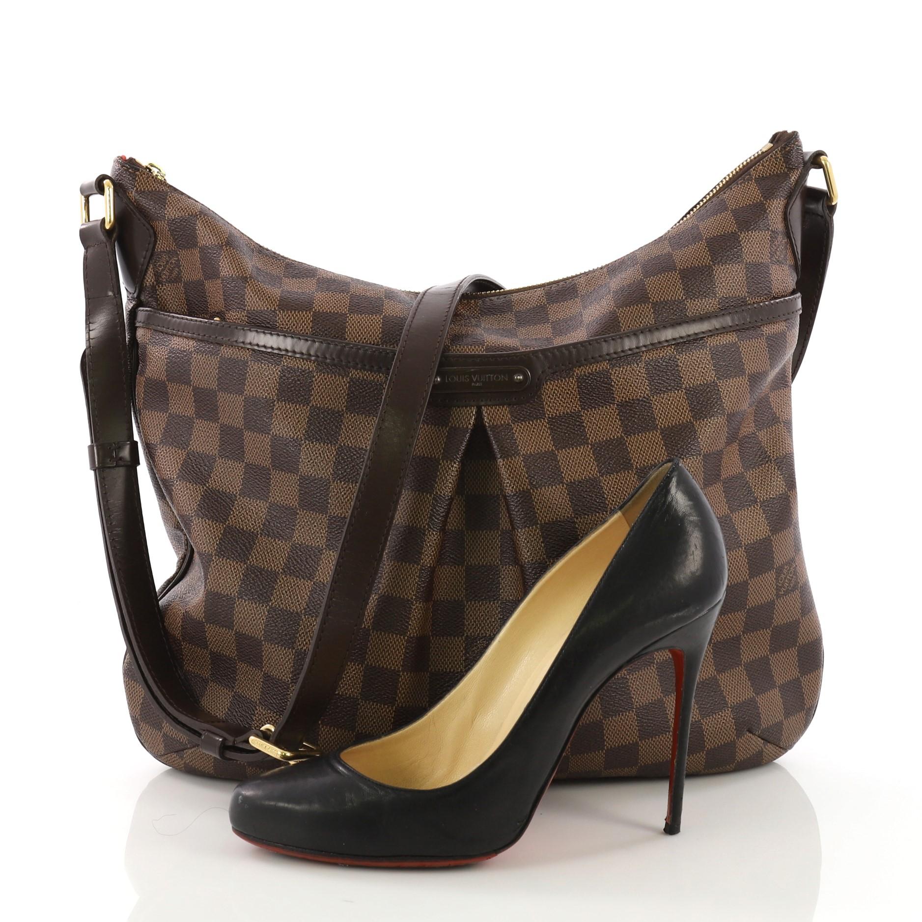 This Louis Vuitton Bloomsbury Handbag Damier GM, crafted from damier ebene coated canvas, features an adjustable leather strap, inverted pleating at the front, front zip pocket, brown leather trim, and gold-tone hardware. Its top zip closure opens