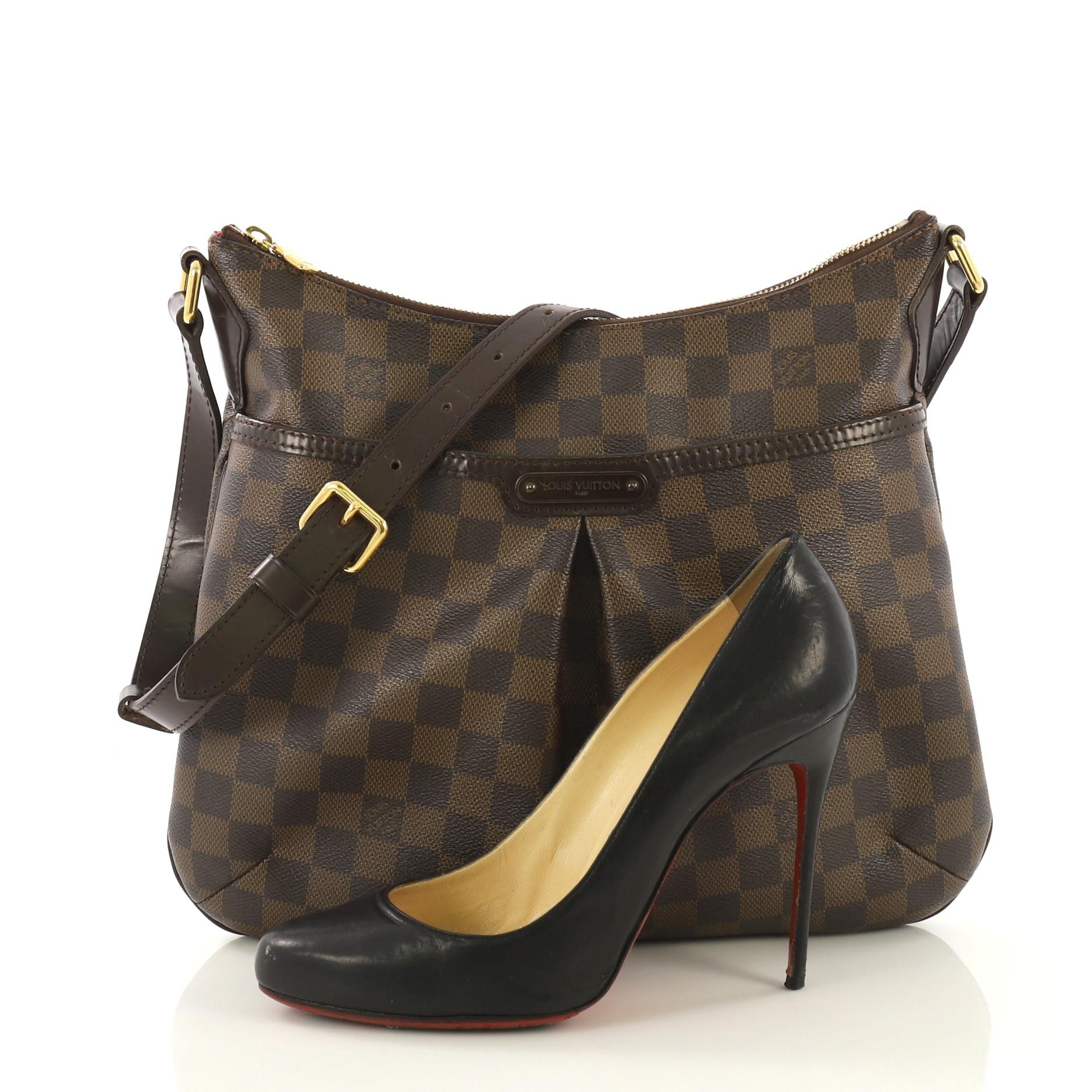 This Louis Vuitton Bloomsbury Handbag Damier PM, crafted from damier ebene coated canvas, features an adjustable leather strap, inverted pleating at the front, front pocket and gold-tone hardware. Its top zip closure opens to a red fabric interior