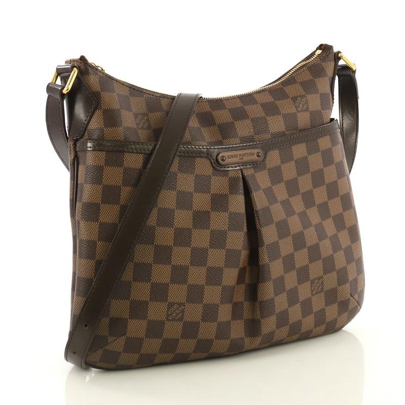 This Louis Vuitton Bloomsbury Handbag Damier PM, crafted from damier ebene coated canvas, features an adjustable leather strap, inverted pleating at the front, exterior front pocket, leather trim, and gold-tone hardware. Its top zip closure opens to