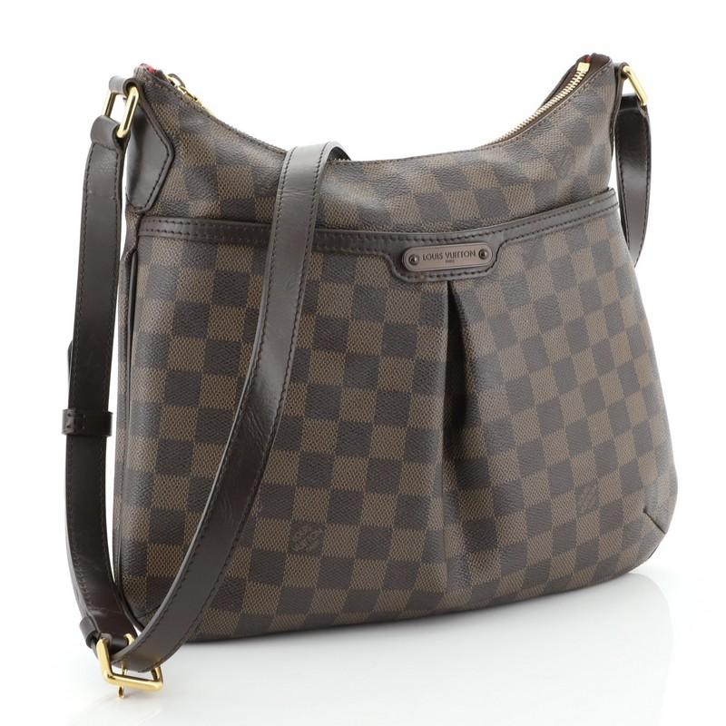 This Louis Vuitton Bloomsbury Handbag Damier PM, crafted from damier ebene coated canvas, features an adjustable leather strap, inverted pleating at the front, exterior front pocket, leather trim, and gold-tone hardware. Its top zip closure opens to