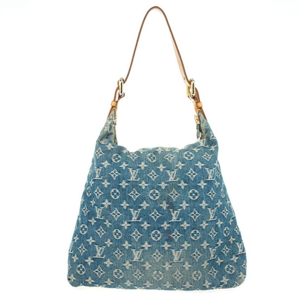 This slouchy Louis Vuitton Blue Denim Monogram Baggy GM bag is the ideal hobo to sling on your shoulders. It is crafted from monogram denim with beige leather trim and gold-tone hardware. It features a top and front zip closure and two front flap