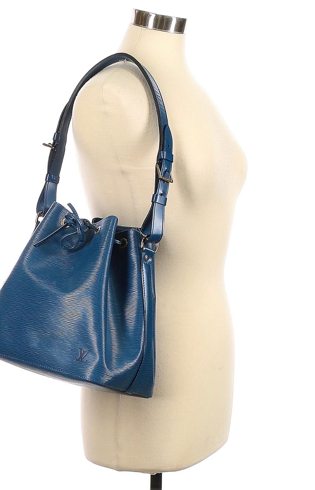 If there are any unspoken accessorizing rules, it's that a bucket bag is a must in any wardrobe. This petite Noé silhouette by Louis Vuitton is cut from blue Epi leather with gold-tone hardware for subtle shine. Loosen the drawstring to reveal a
