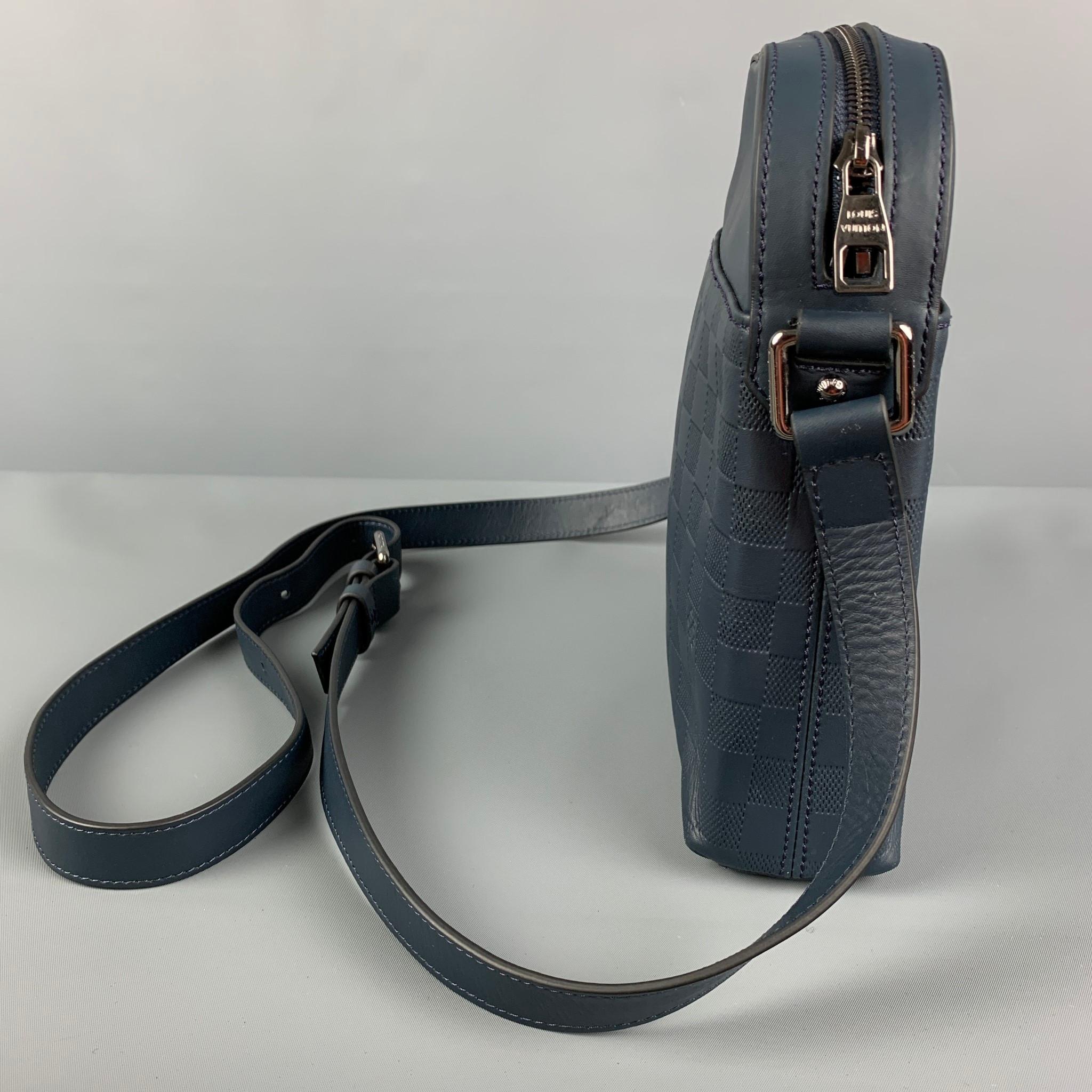 LOUIS VUITTON 'Infini District Pochette' bag comes in a blue damier leather featuring a messenger style, adjustable crossbody strap, silver tone hardware, inner pocket, and a zipper closure. Includes dust bag. Made in France. 

Very Good Pre-Owned