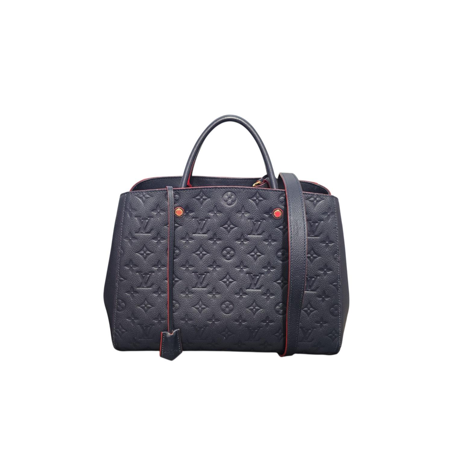 Diese schicke Handtasche ist aus Louis Vuitton-Leder mit Monogramm-Prägung in Marineblau mit roten Paspeln gefertigt. Die Handtasche verfügt über gerollte Ledergriffe mit goldfarbenen Messinggliedern und eine breite, offene Klappe, die ein rot