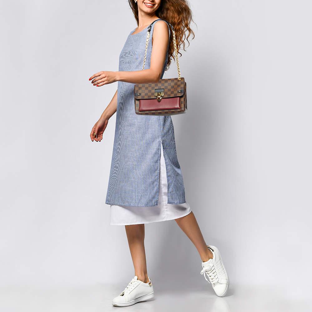 This Louis Vuitton Vavin PM bag has been beautifully crafted using Damier Ebene canvas and bordeaux leather. The flap is adorned with a branded gold tone lock and the top is attached with a sliding chain handle.