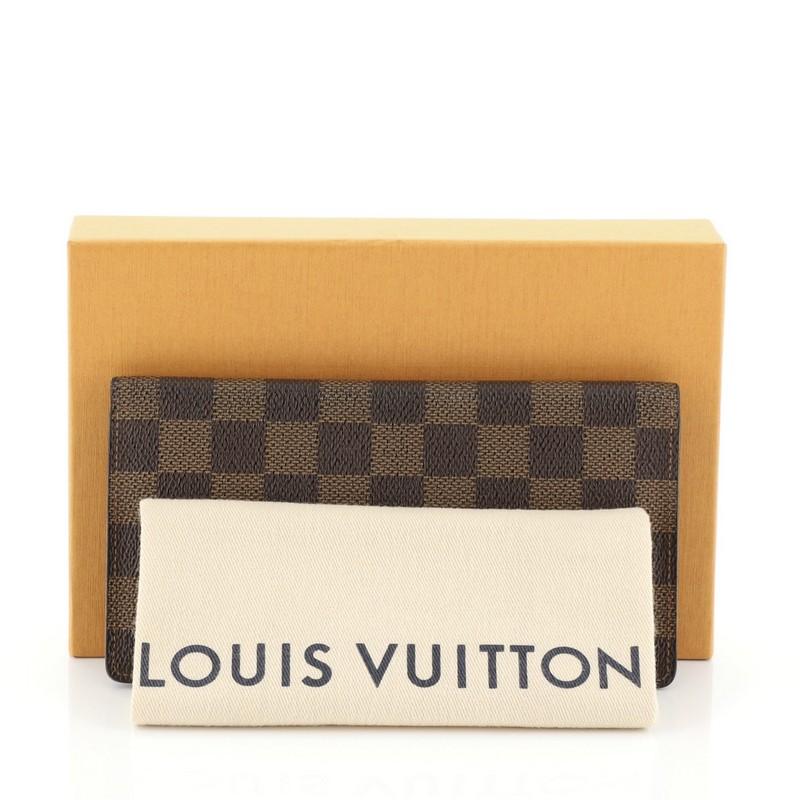 This Louis Vuitton Brazza Wallet Damier, crafted in damier ebene coated canvas. It opens to a brown leather interior with multiple card slots and zip and slip pockets. Authenticity code reads: MI0063. 

Estimated Retail Price: $705
Condition: Very