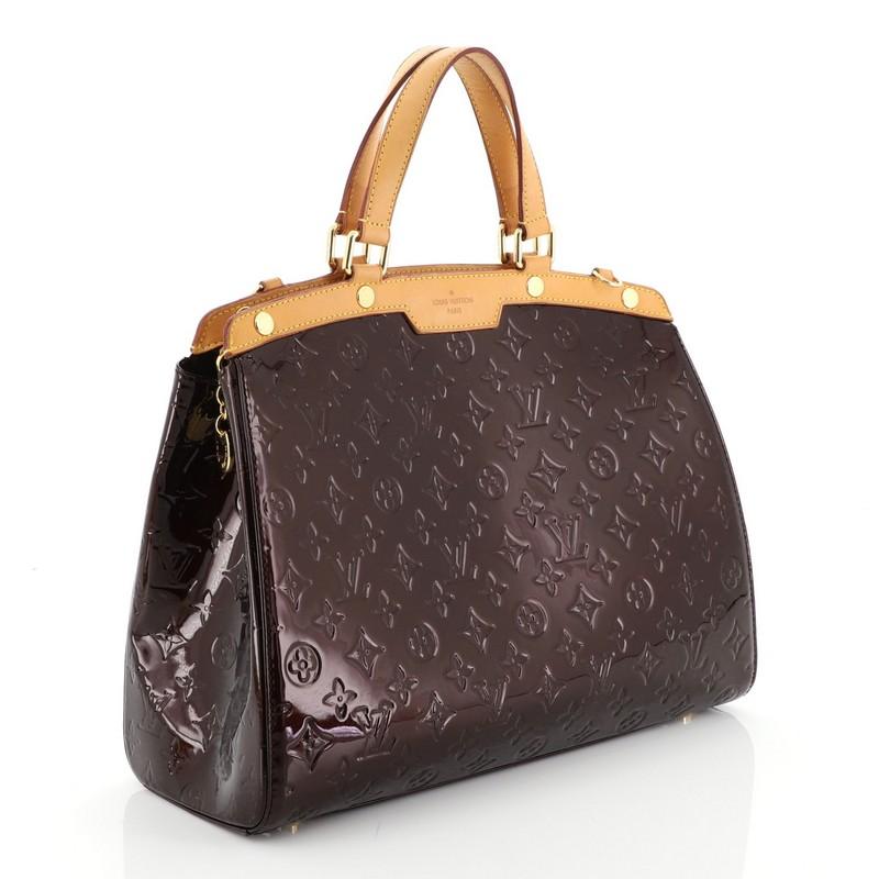 This Louis Vuitton Brea Handbag Monogram Vernis GM, crafted in purple monogram vernis leather with cowhide leather trim, features dual flat handles, protective base studs, and gold-tone hardware. Its top zip closure opens to a brown fabric interior