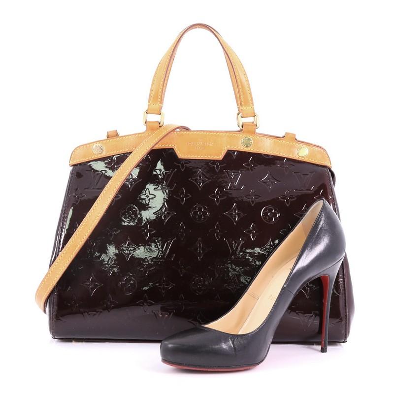 This Louis Vuitton Brea Handbag Monogram Vernis MM, crafted in dark purple monogram vernis leather, features dual flat handles, cowhide leather trims, protective base studs, and gold-tone hardware. Its top zip closure opens to a dark purple fabric
