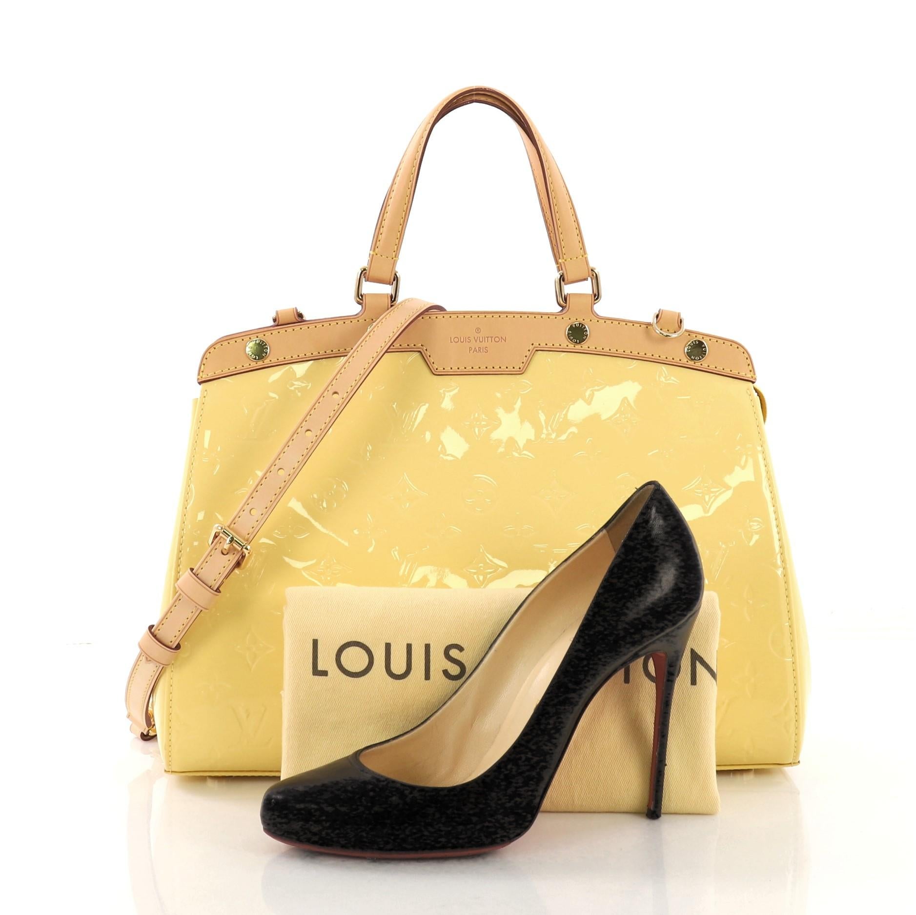 This Louis Vuitton Brea Handbag Monogram Vernis MM, crafted in yellow monogram vernis leather with cowhide leather trim, features dual flat handles, protective base studs, and gold-tone hardware. Its top zip closure opens to a yellow fabric interior