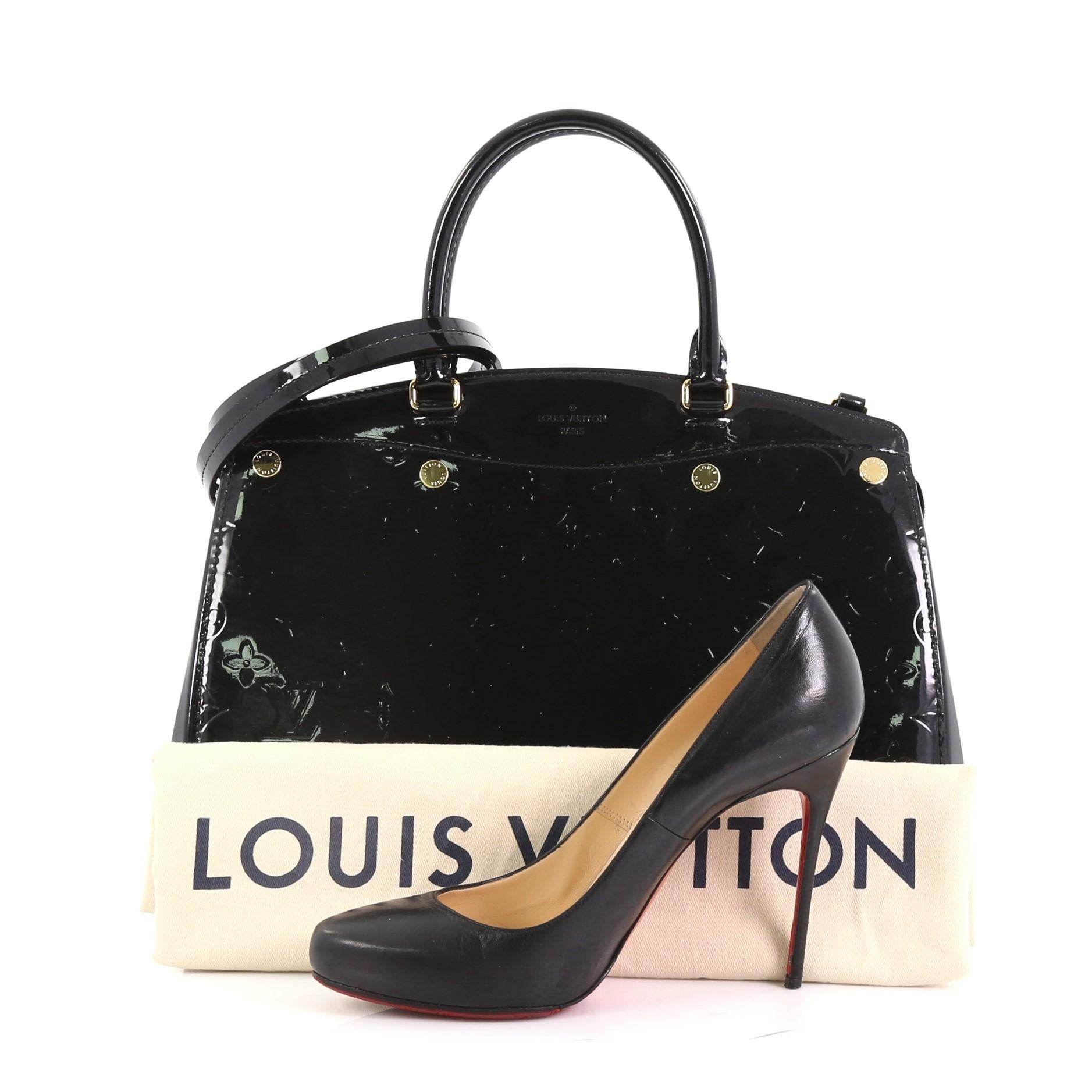 This Louis Vuitton Brea NM Handbag Monogram Vernis MM, crafted in black monogram vernis, features dual rolled handles, protective base studs, and gold-tone hardware. Its top zip closure opens to a black fabric interior with zip and slip pockets.